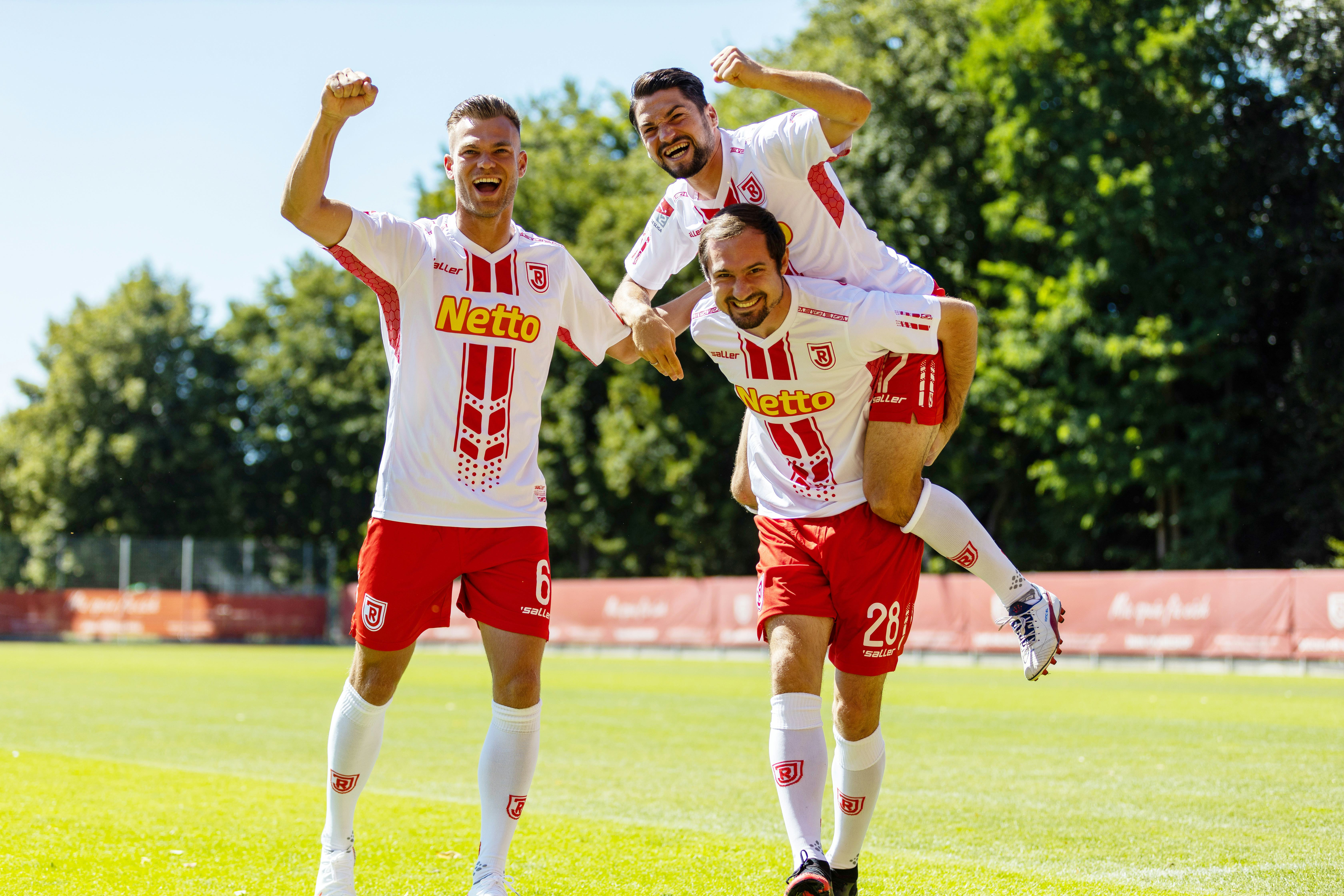 Drei Spieler des SSV Jahn Regensburg jubelnd auf dem Fußballplatz
