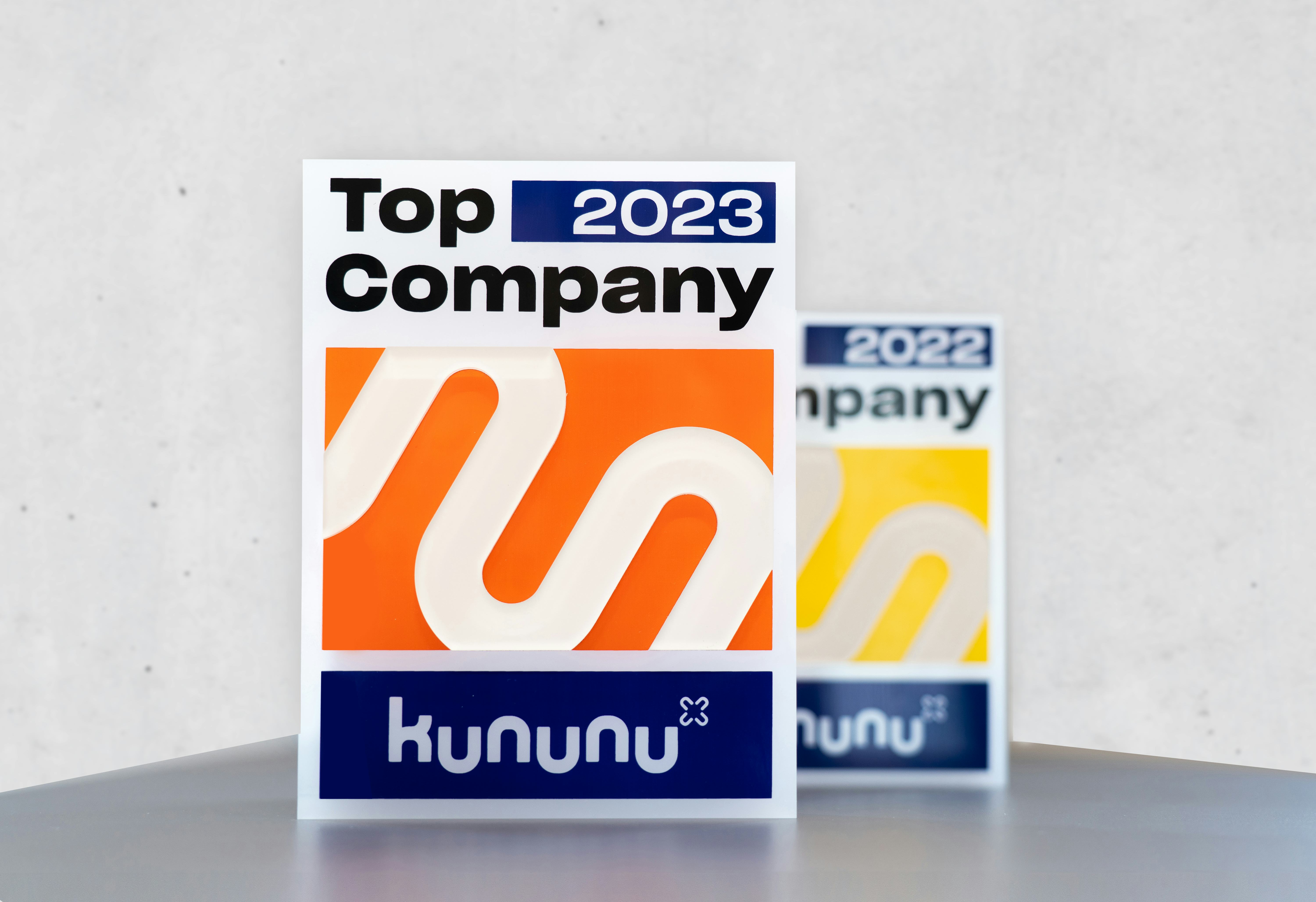 Der Award zu Top Company 2023 steht auf einem Tisch, im Hintergrund der Award von 2022