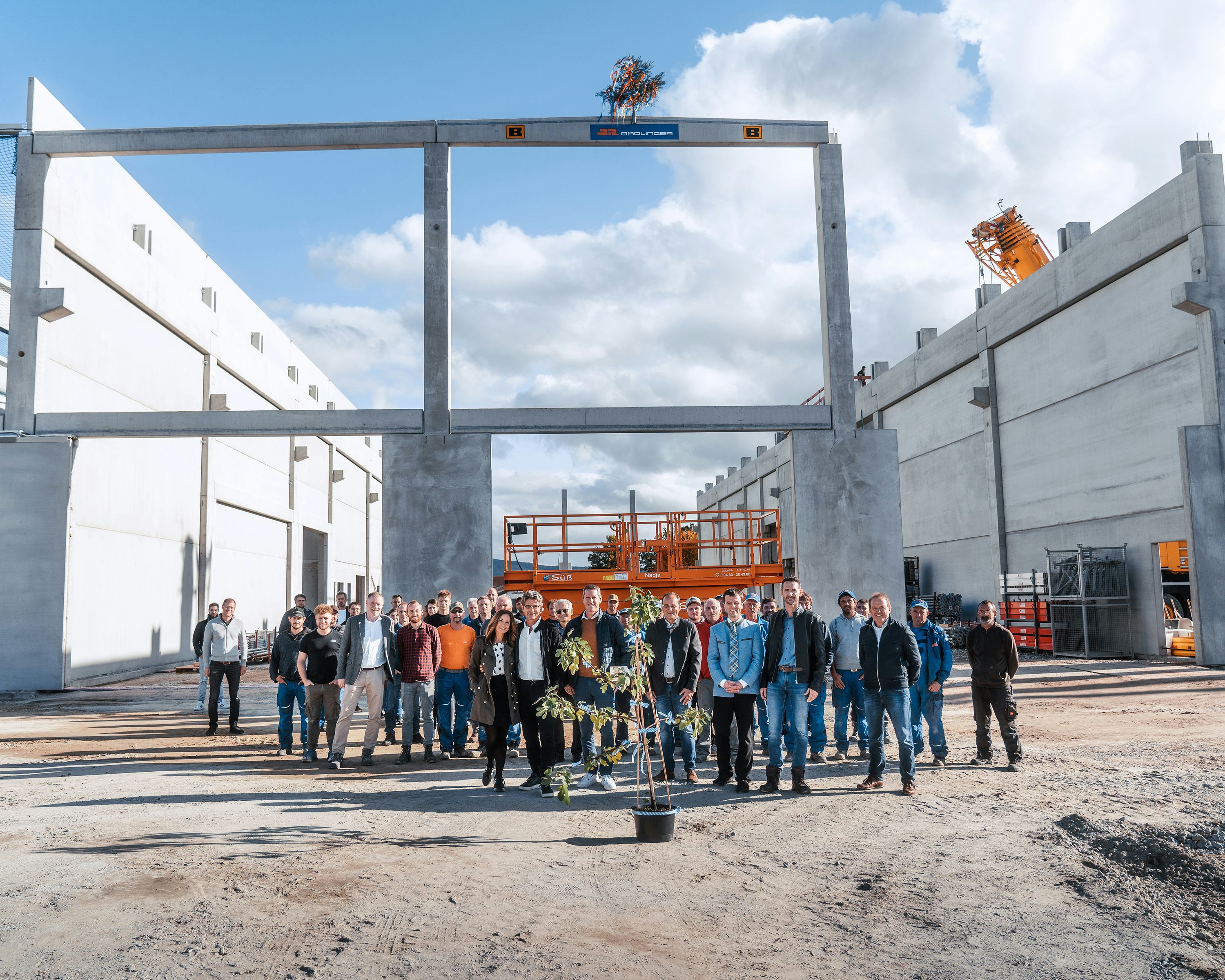 Gruppenfoto der Besucher des Richtfests mit Rohbau im Hintergrund