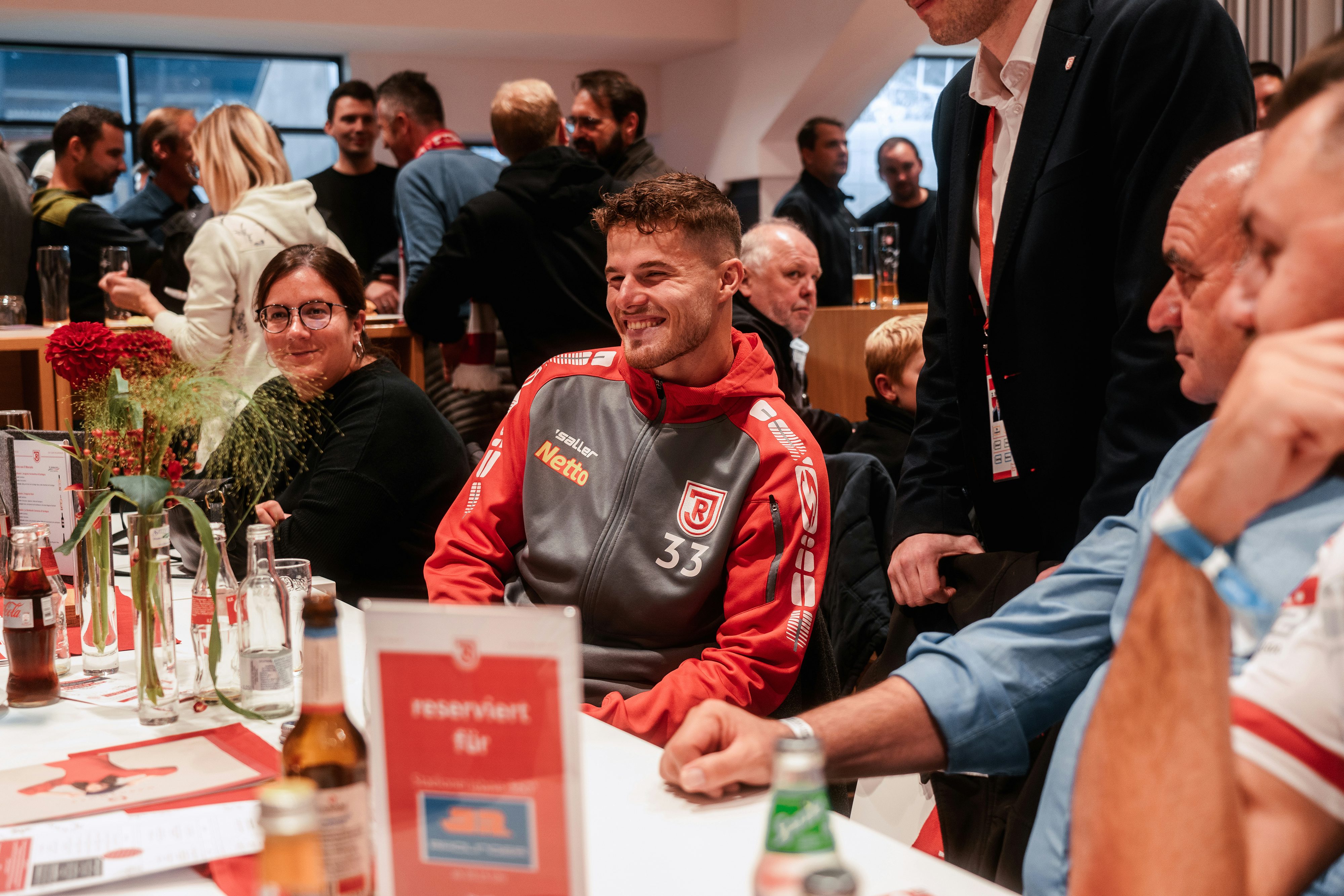 Rädlinger Mitarbeiter sitzen mit Jahn Spieler Jan Elvedi an einem Tisch im Business Bereich des Jahnstadion Regensburg