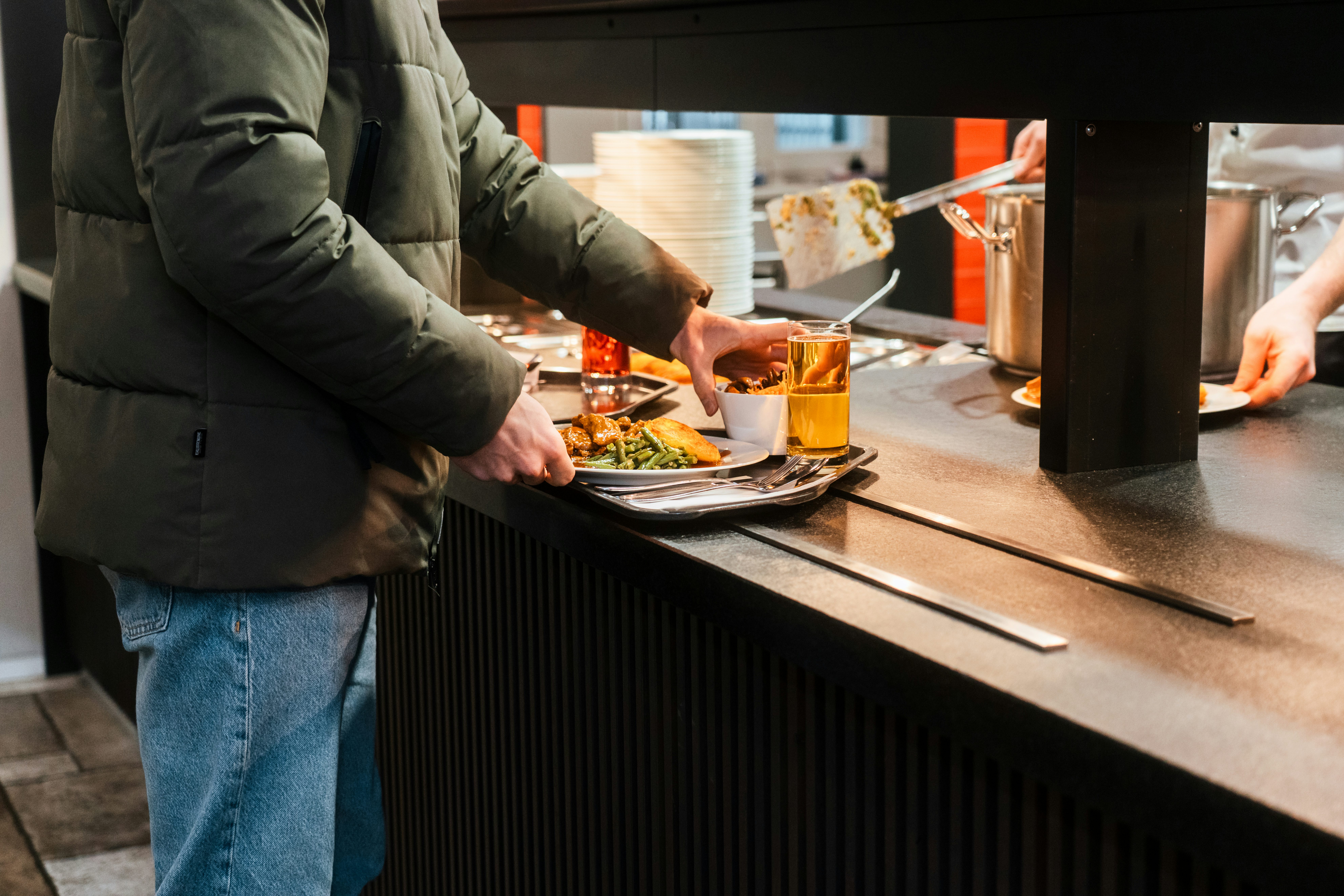 Mitarbeiter im 's Kloster bei der Essensausgabe, Detailaufnahme des Tabletts mit Hauptgericht, Salat und Getränk