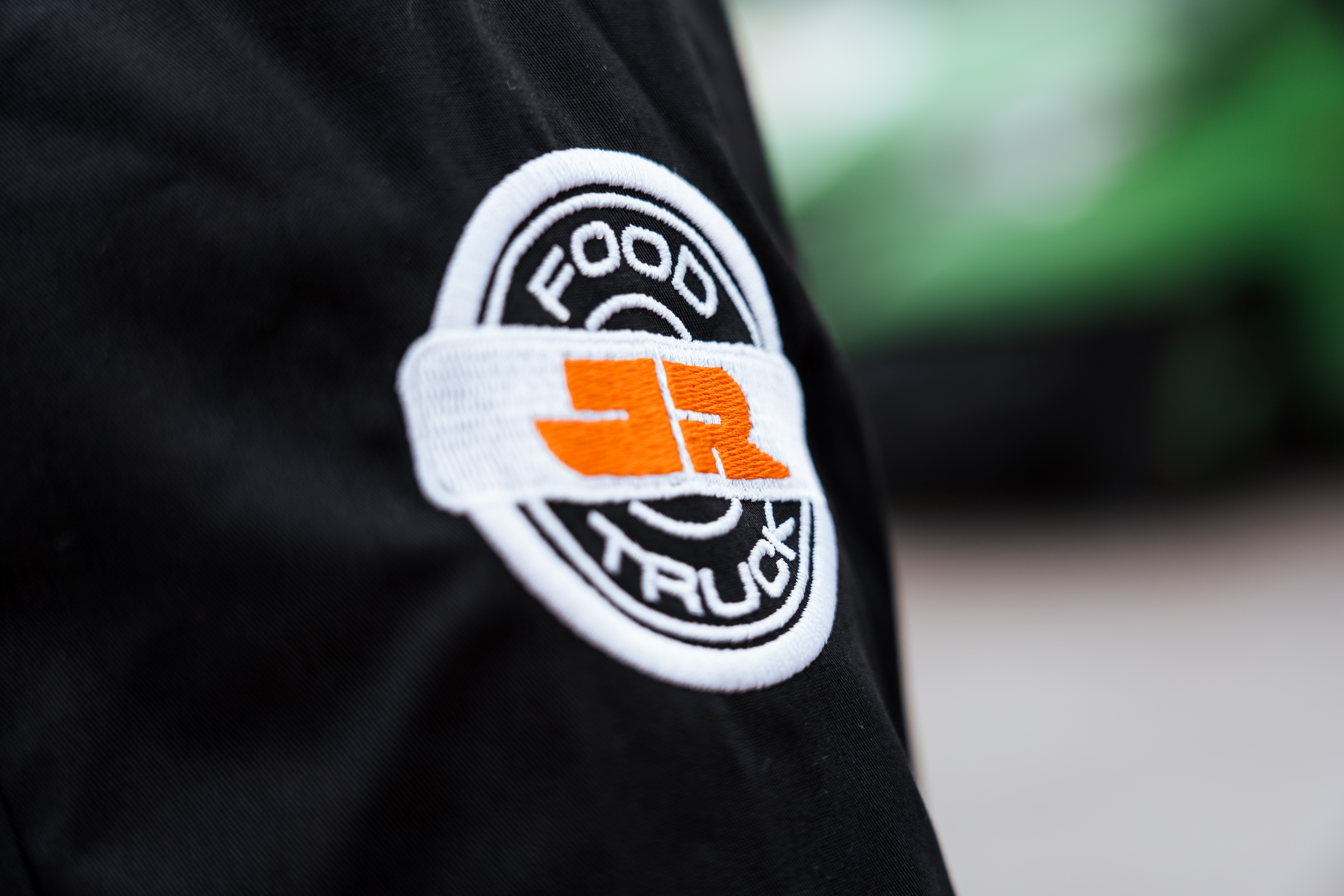 JR Foodtruck: gesticktes Foodtruck-Logo auf dem Hemd eines Foodtruck-Kochs, Detailaufnahme