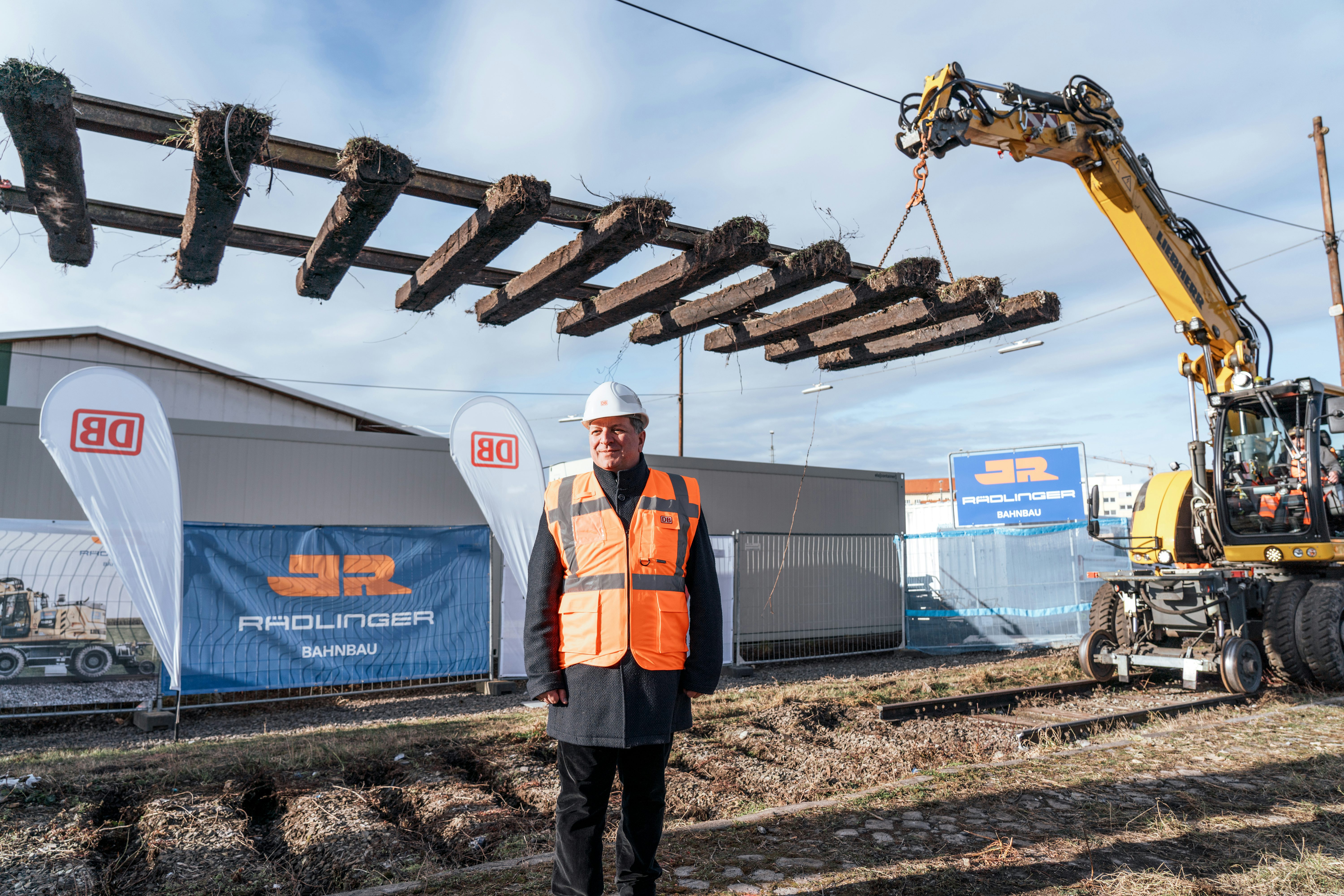 Bayerns Verkehrsminister Christian Bernreiter beim Spatenstich für den Neubau der Autoreisezuganlage in München; im Hintergrund Bagger beim Aushub eines Gleises