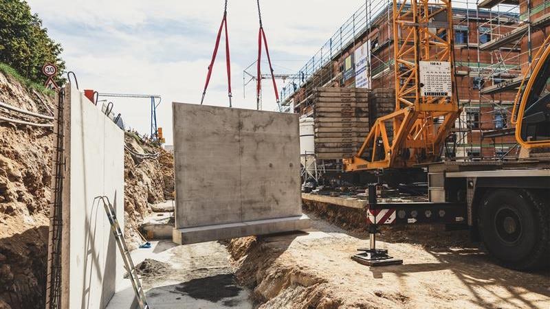 Kran hebt Beton-Fertigteil auf einer Baustelle ein