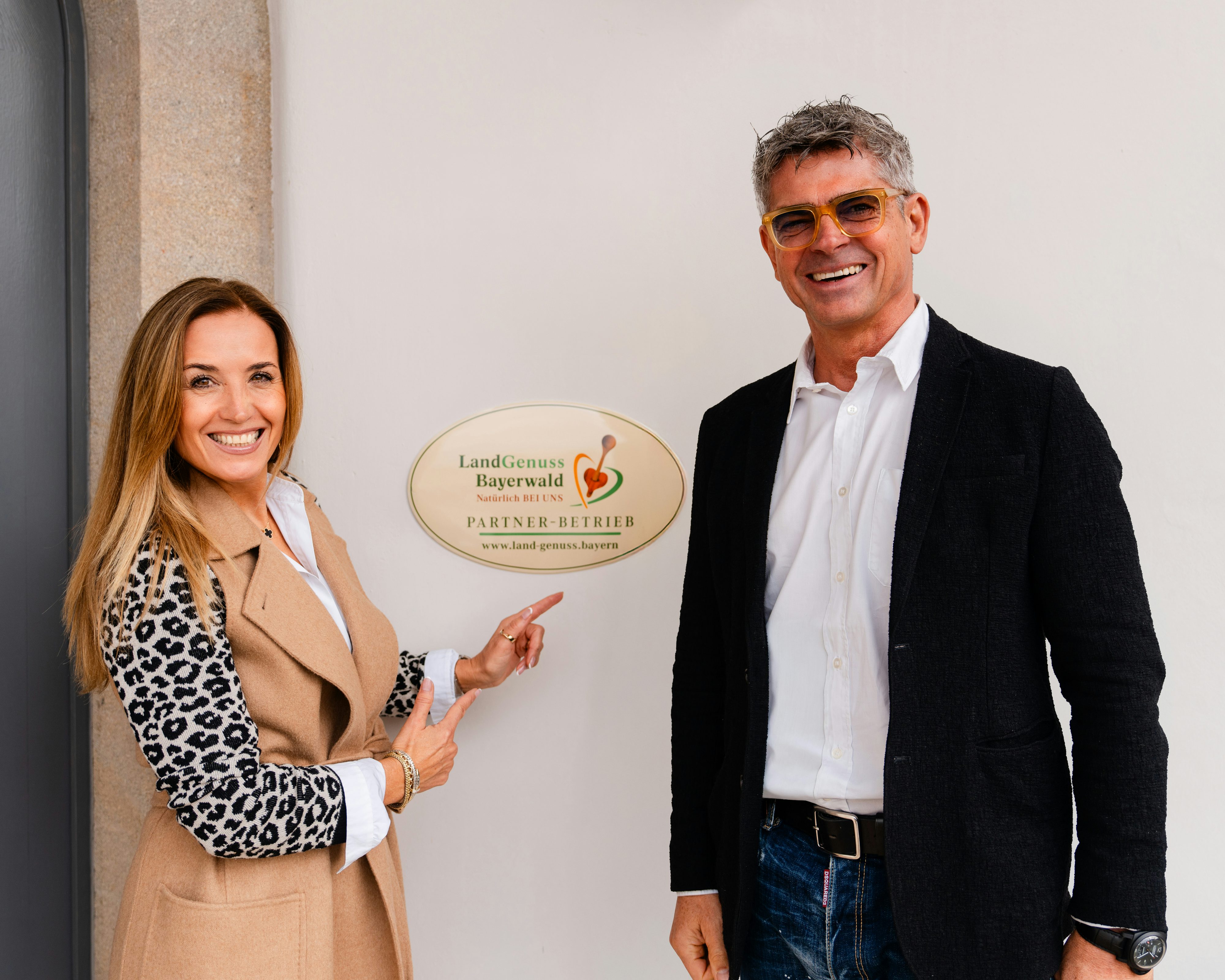 Petra und Josef Rädlinger vor dem Schild, auf dem steht, dass das 's Kloster Partnerbetrieb von LandGenuss Bayerwald ist