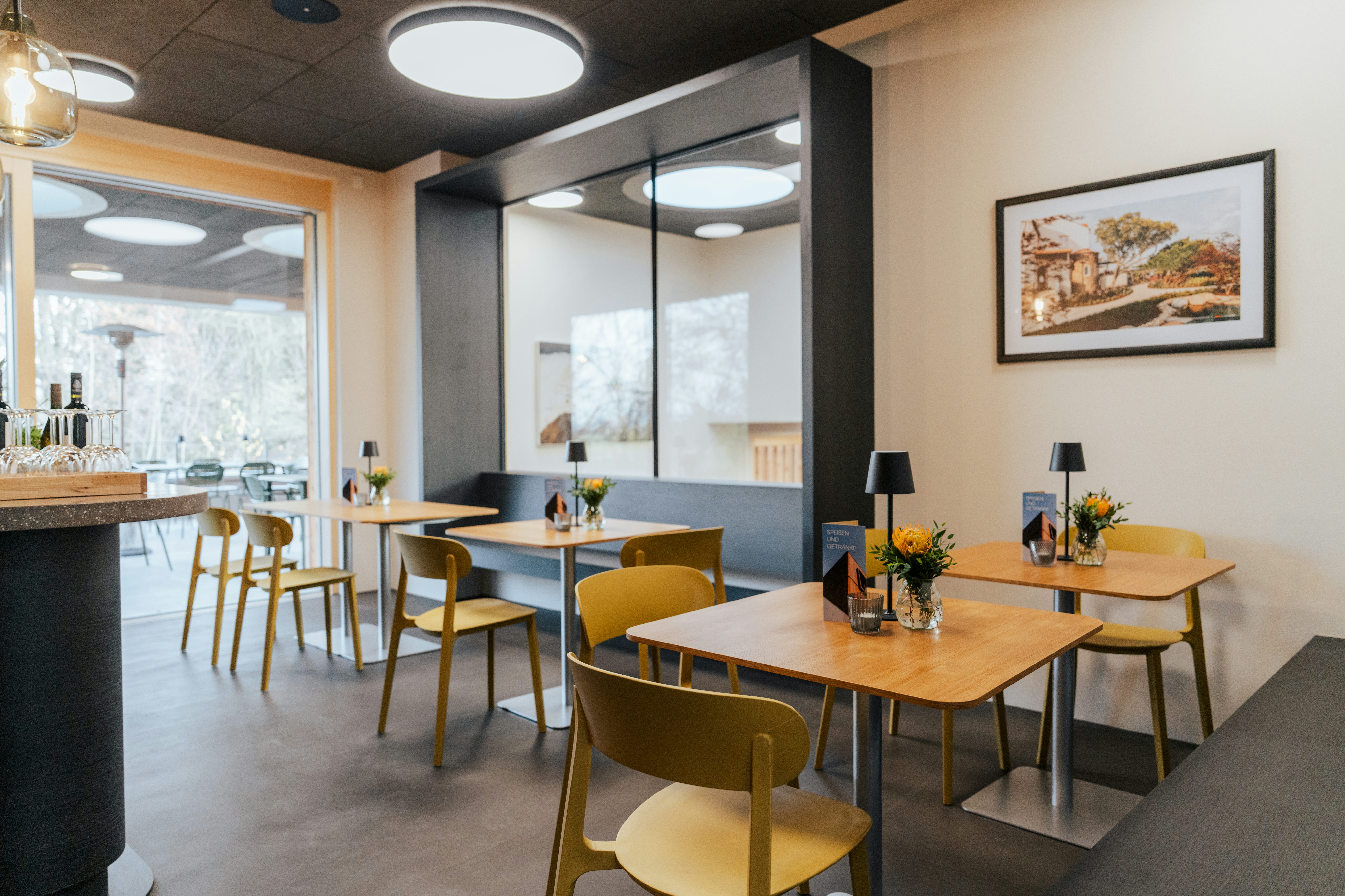 Blick ins neue Bistro im Gebäude mit mehreren Holztischen und Stühlen in einem lichtdurchfluteten Raum