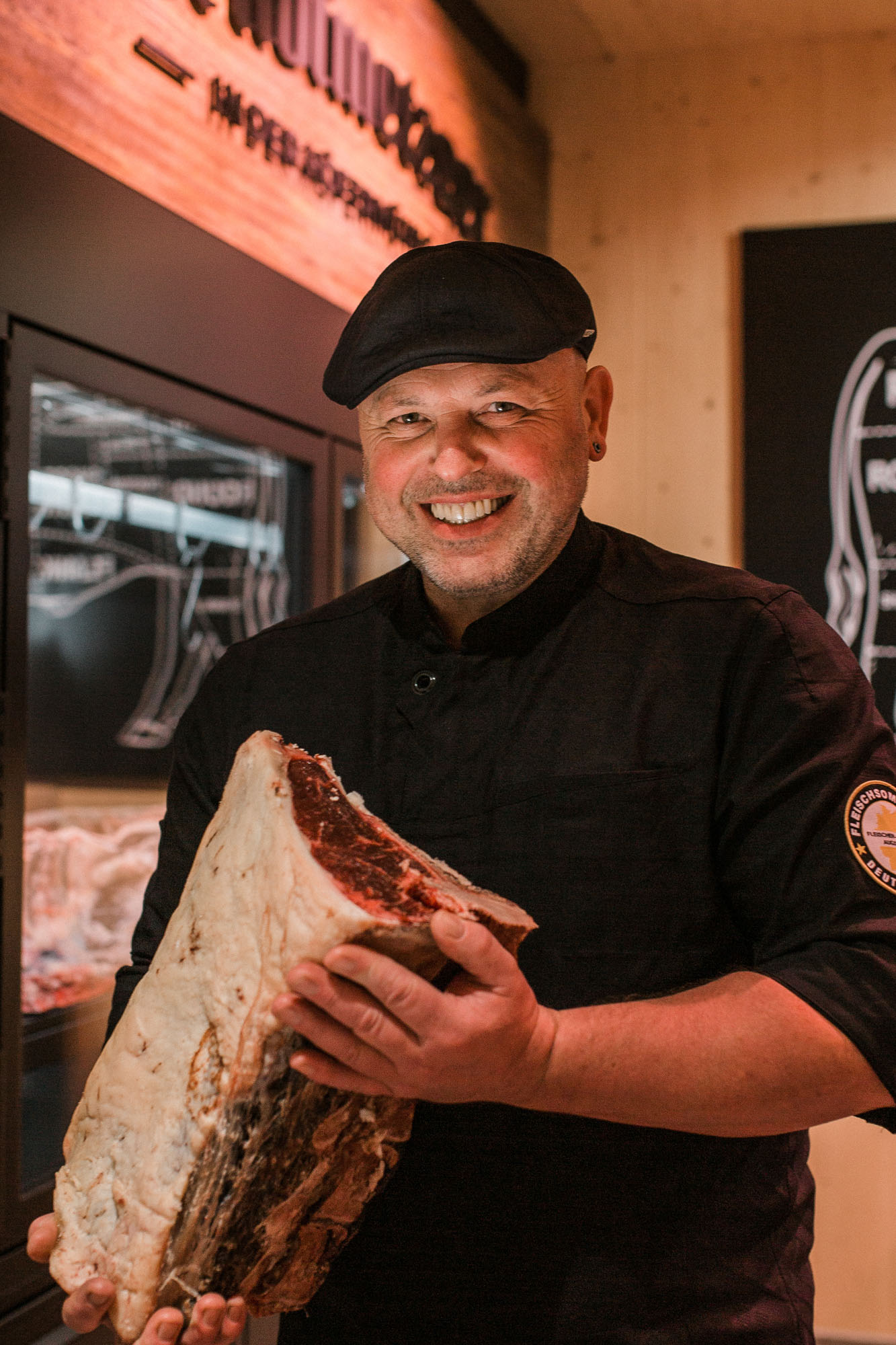 Metzger hält ein großes Stück Fleisch in beiden Händen in einem modernen Hofladen