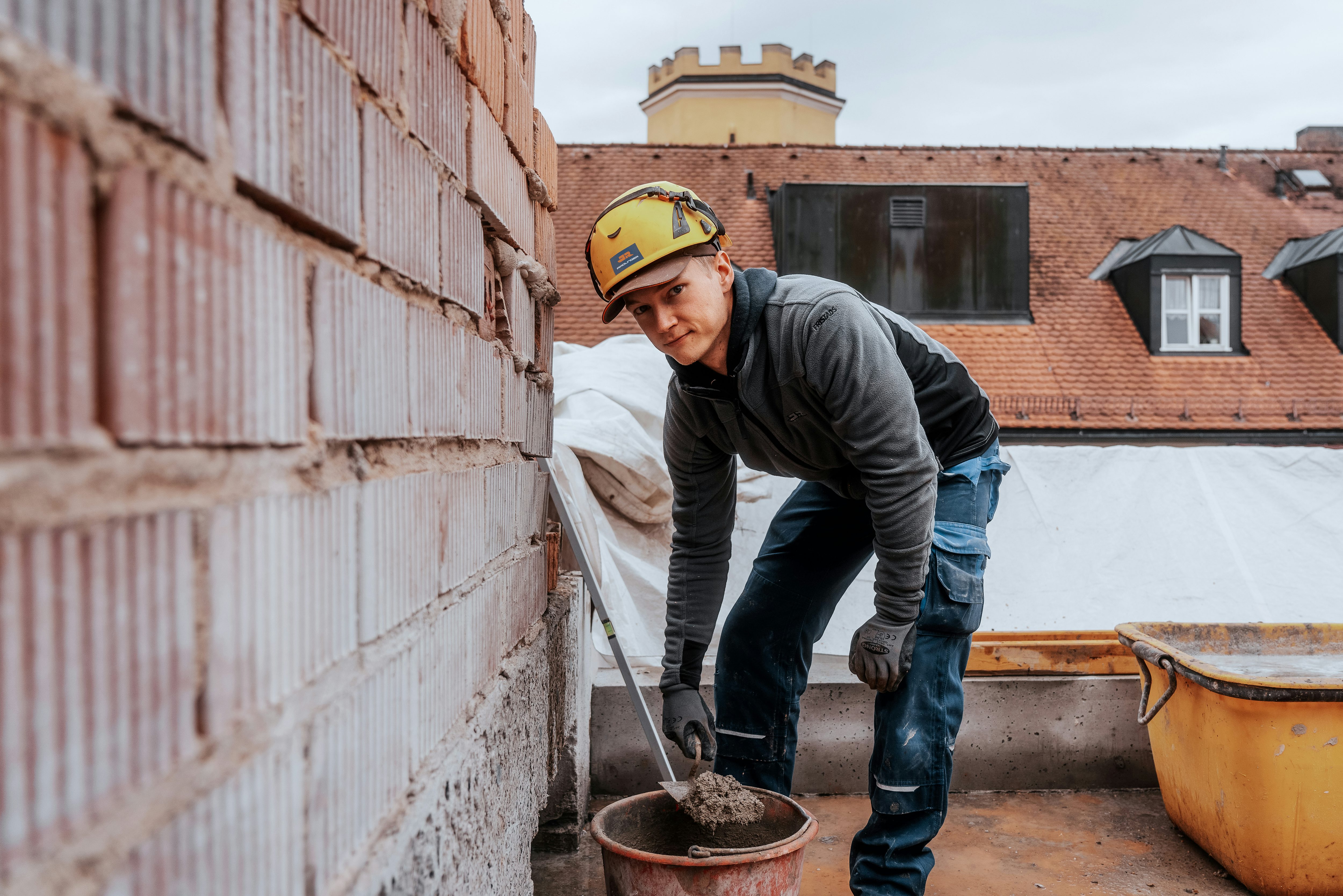 Lukas, Auszubildender zum Maurer bei Rädlinger, auf einer Hochbau-Baustelle beim Mauern einer Wand