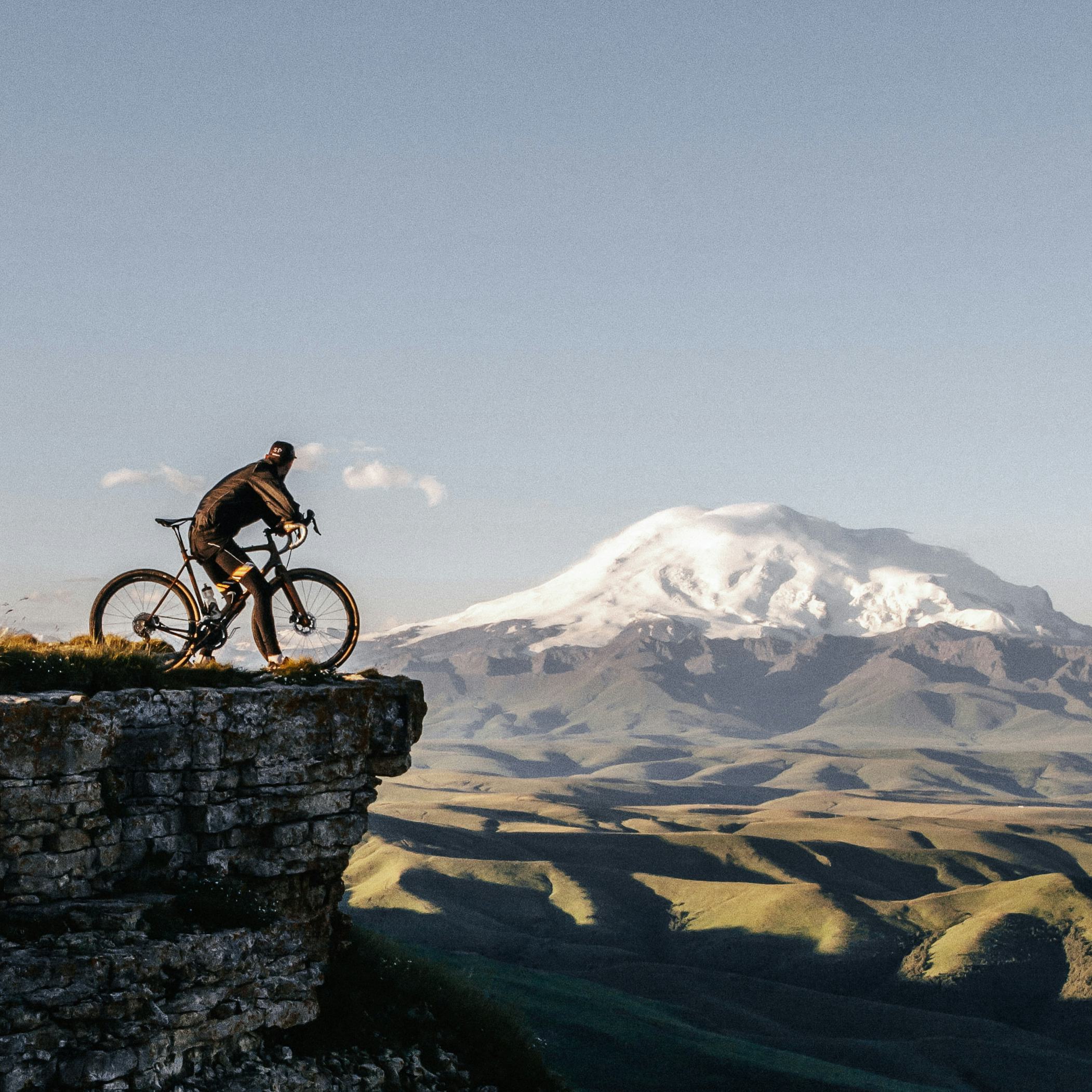 Rädlinger Bikeleasing, Mann steht mit Fahrrad an einer Bergklippe und sieht ins Tal