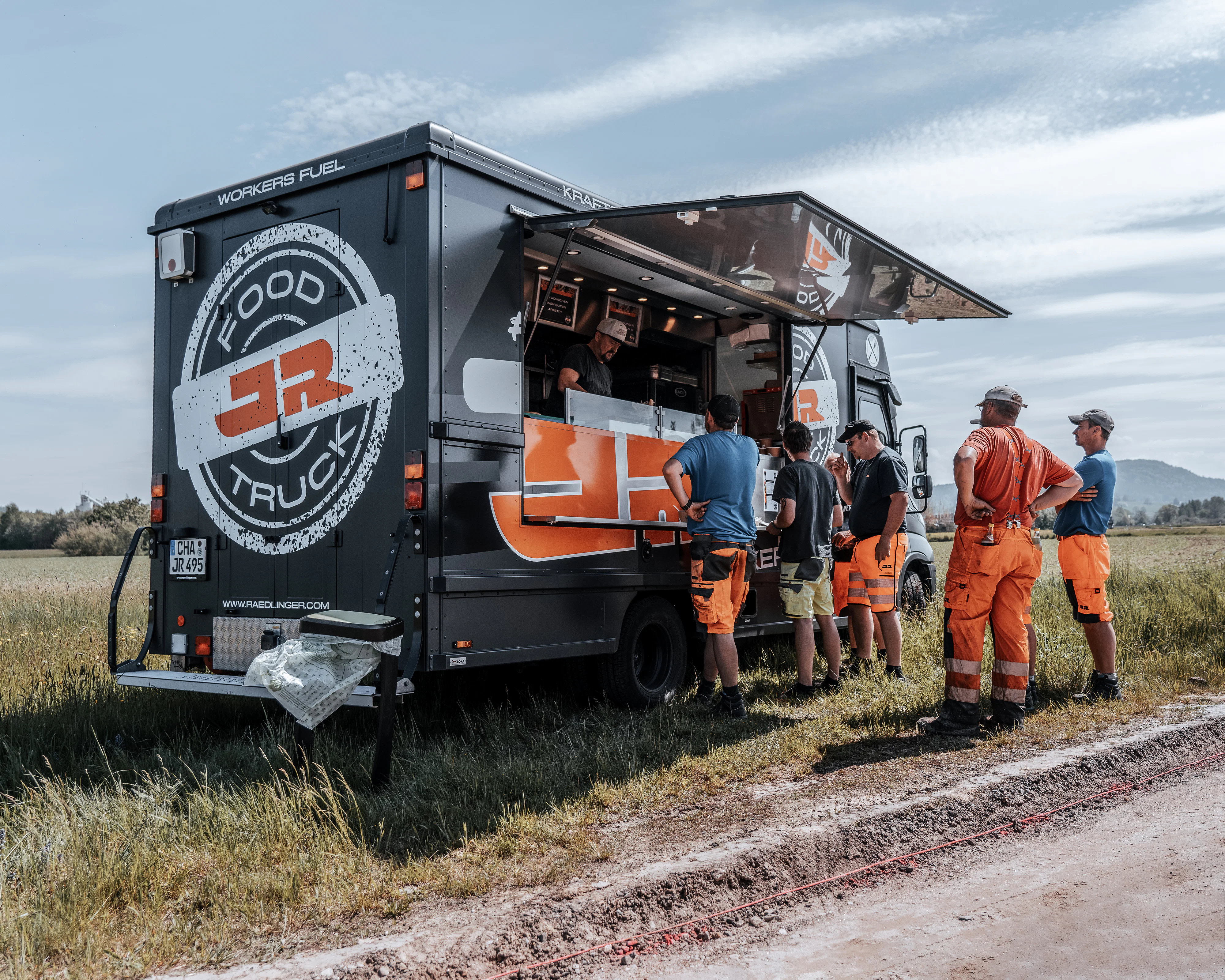 Baustellenarbeiter stehen vor Rädlinger Foodtruck in der Schlange und warten auf ihr Essen