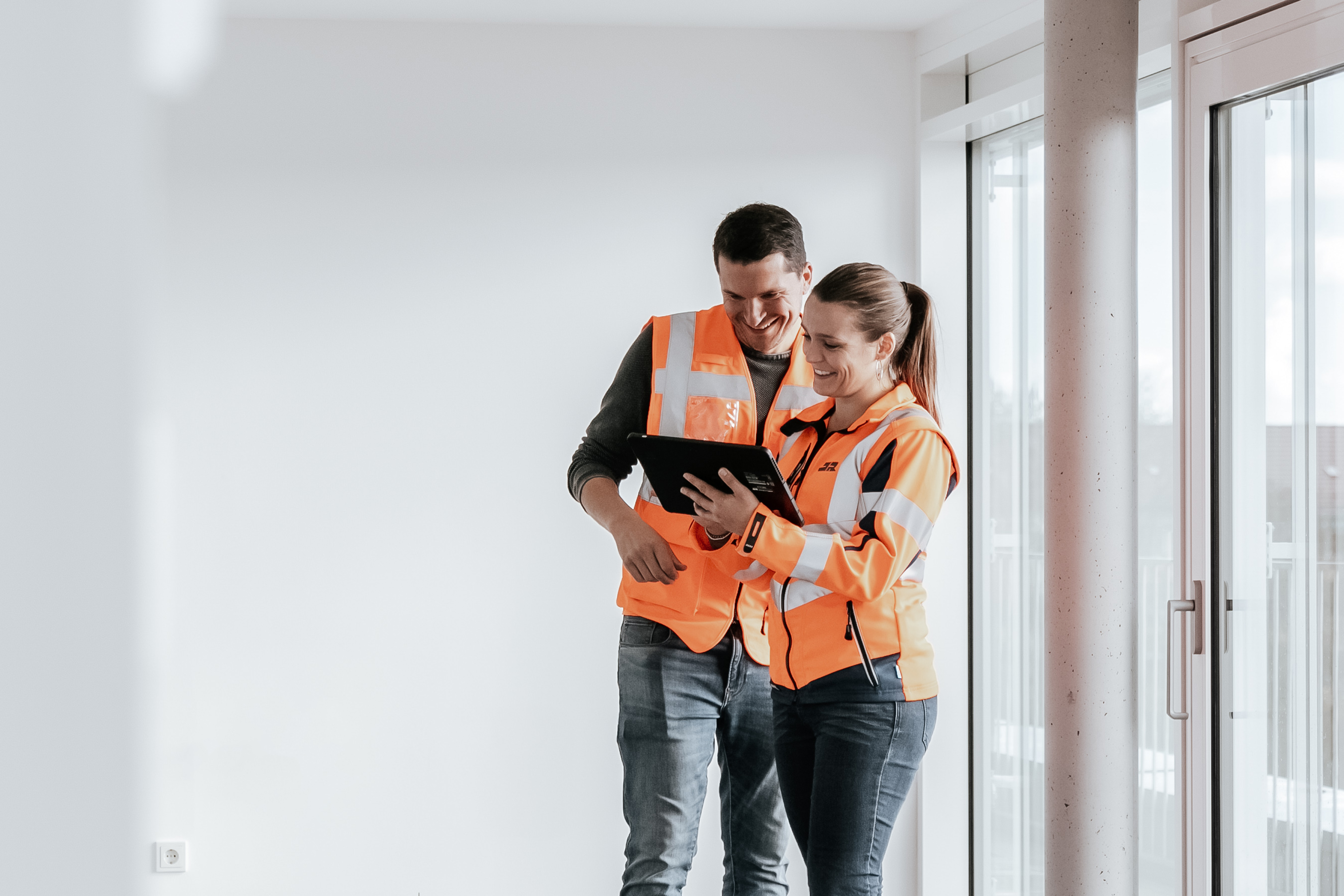 Bauleiterin und Bauleiter bei Abnahme eines Rädlinger Projekts mit Warnweste und Tablet