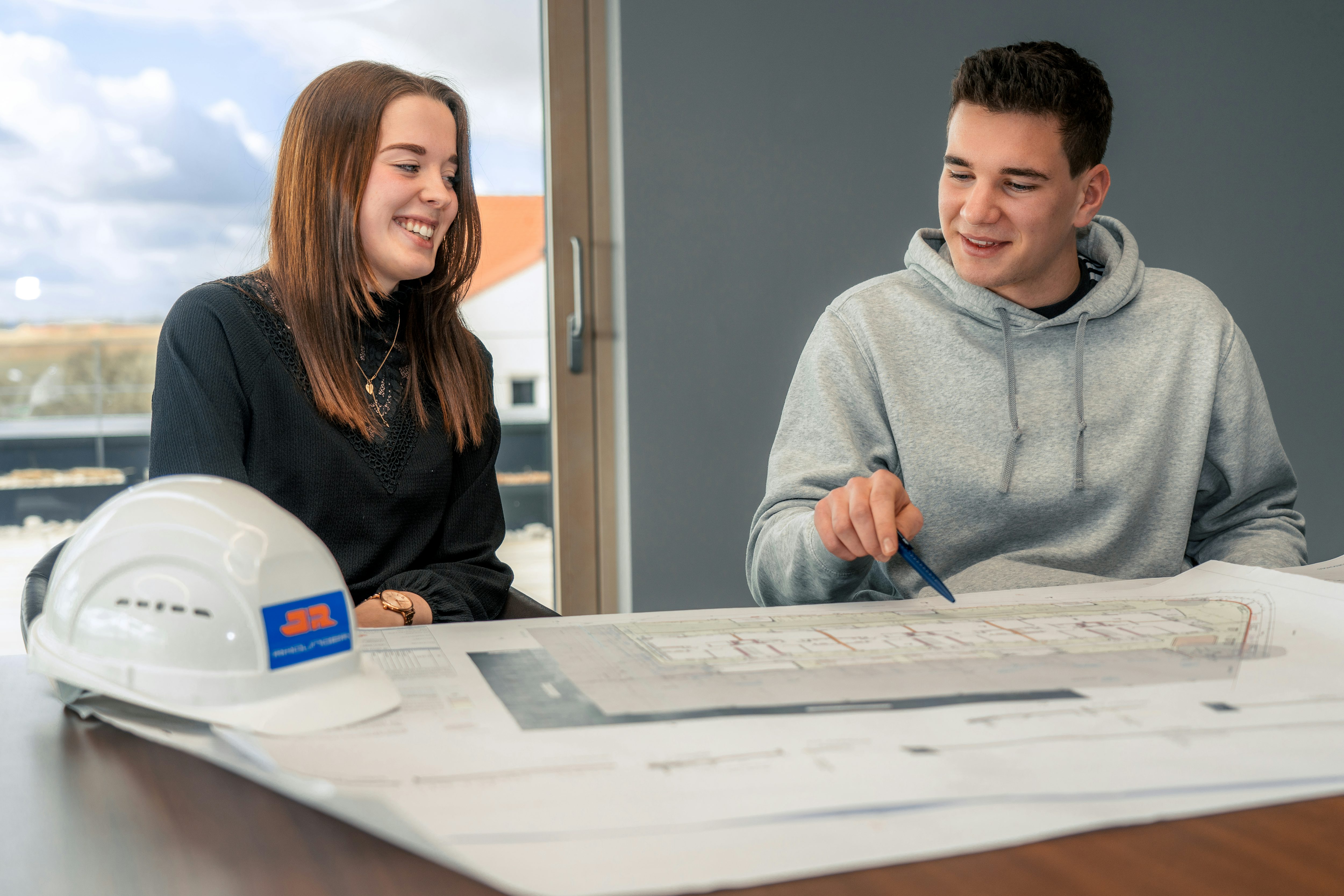 Zwei Studierende bei Rädlinger sehen sich Bauplan an