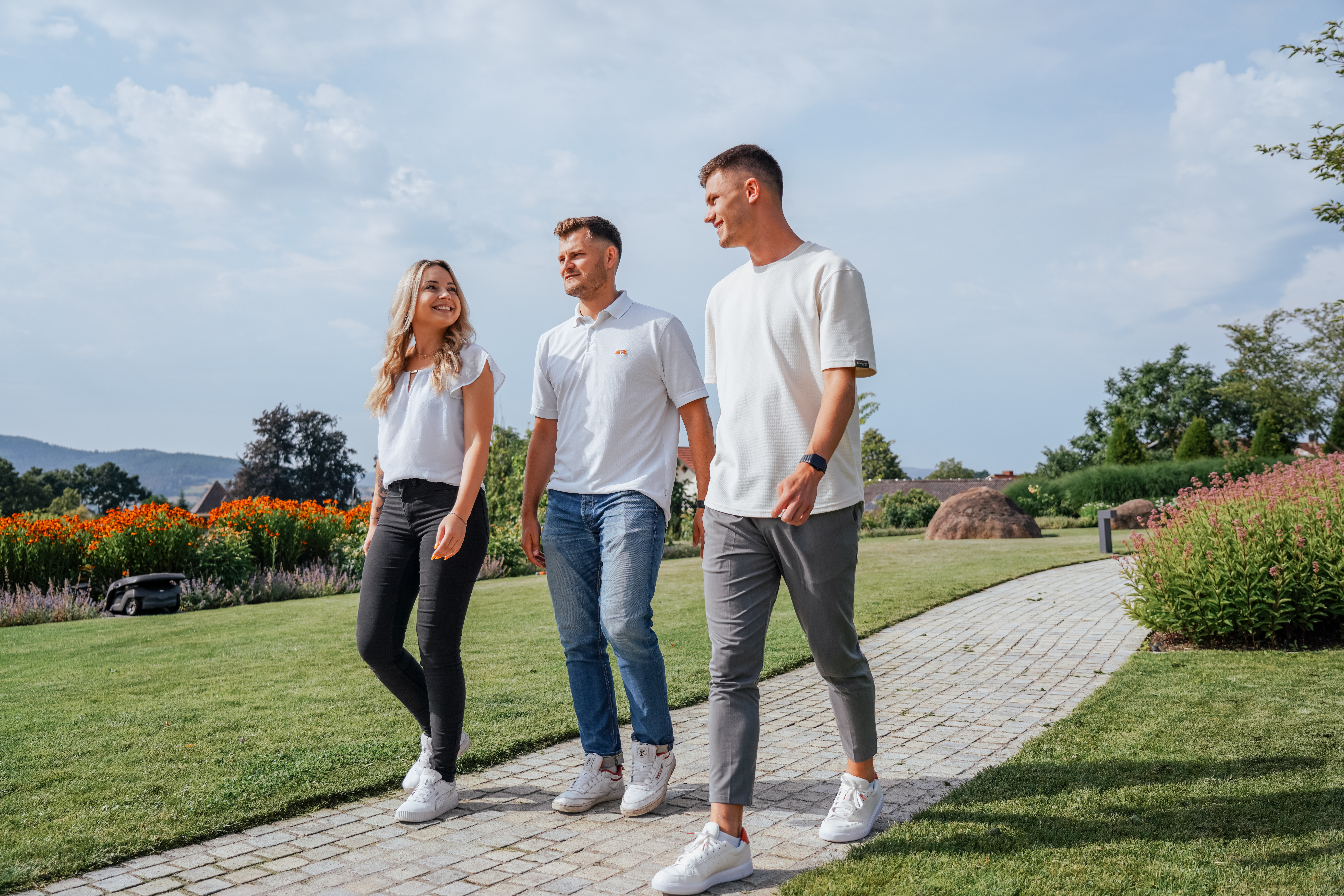 Drei JR Mitarbeitende gehen durch den Firmengarten an der Hauptverwaltung in Cham