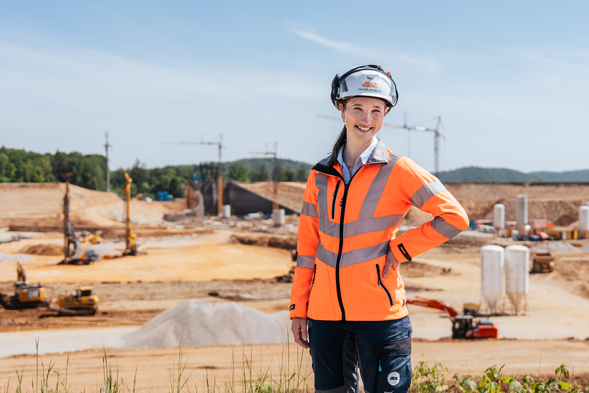 Portrait einer Bauleiterin mit Helm und Warnweste, im Hintergrund die Großbaustelle am Pumpspeicherkraftwerk in Happurg