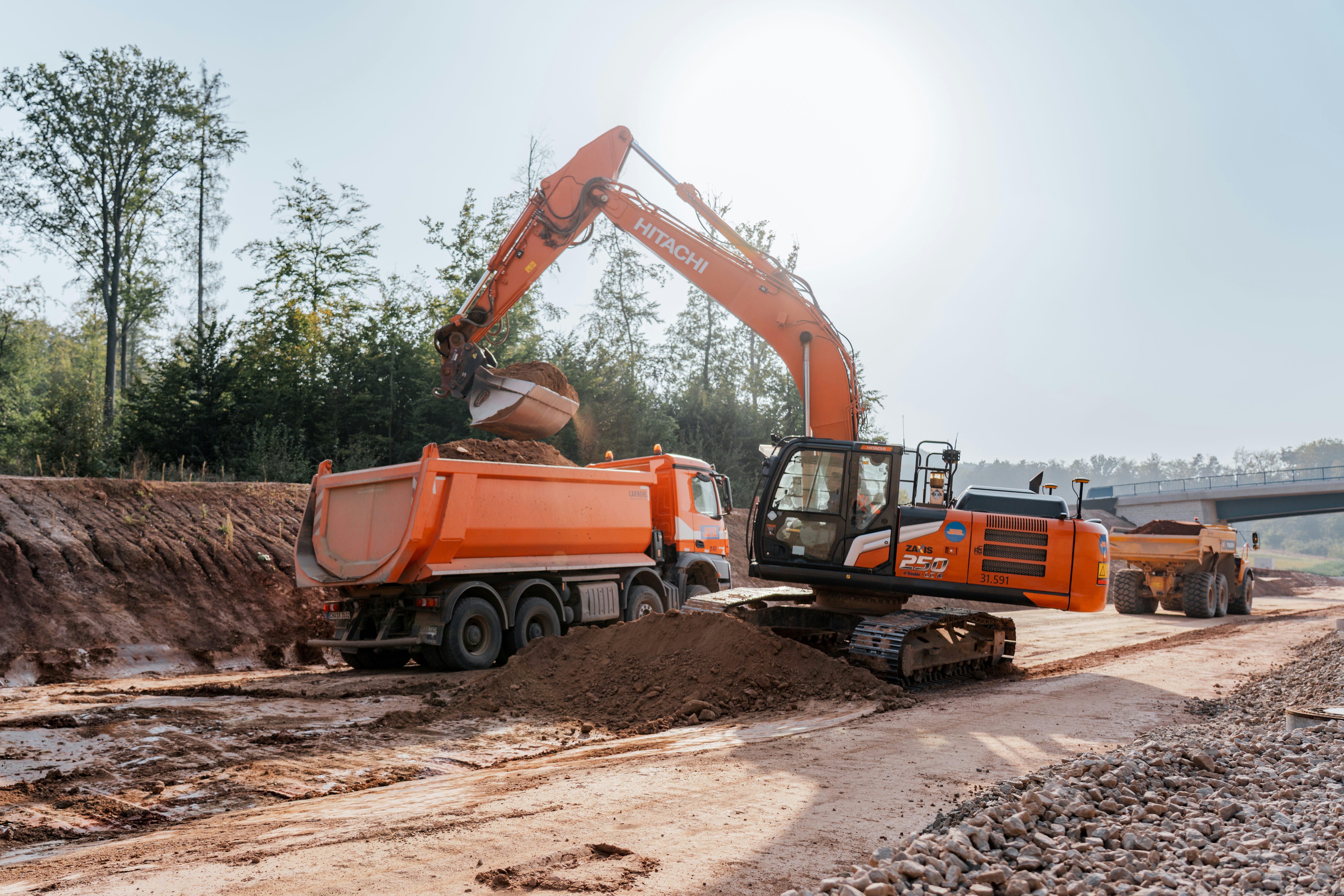 Bagger belädt auf einer Straßenbaustelle Lkw mit Erdreich