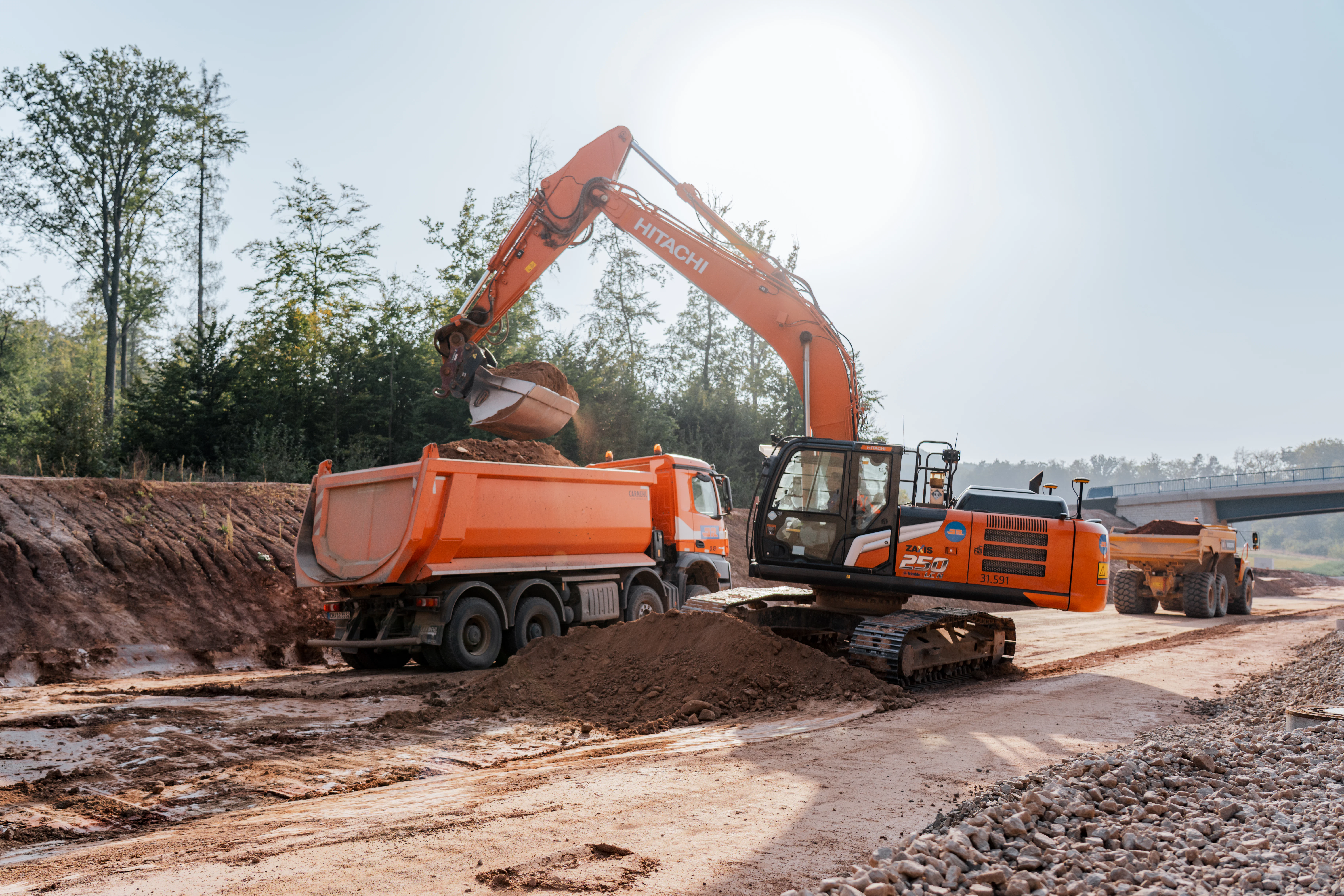 Bagger belädt auf einer Straßenbaustelle Lkw mit Erdreich