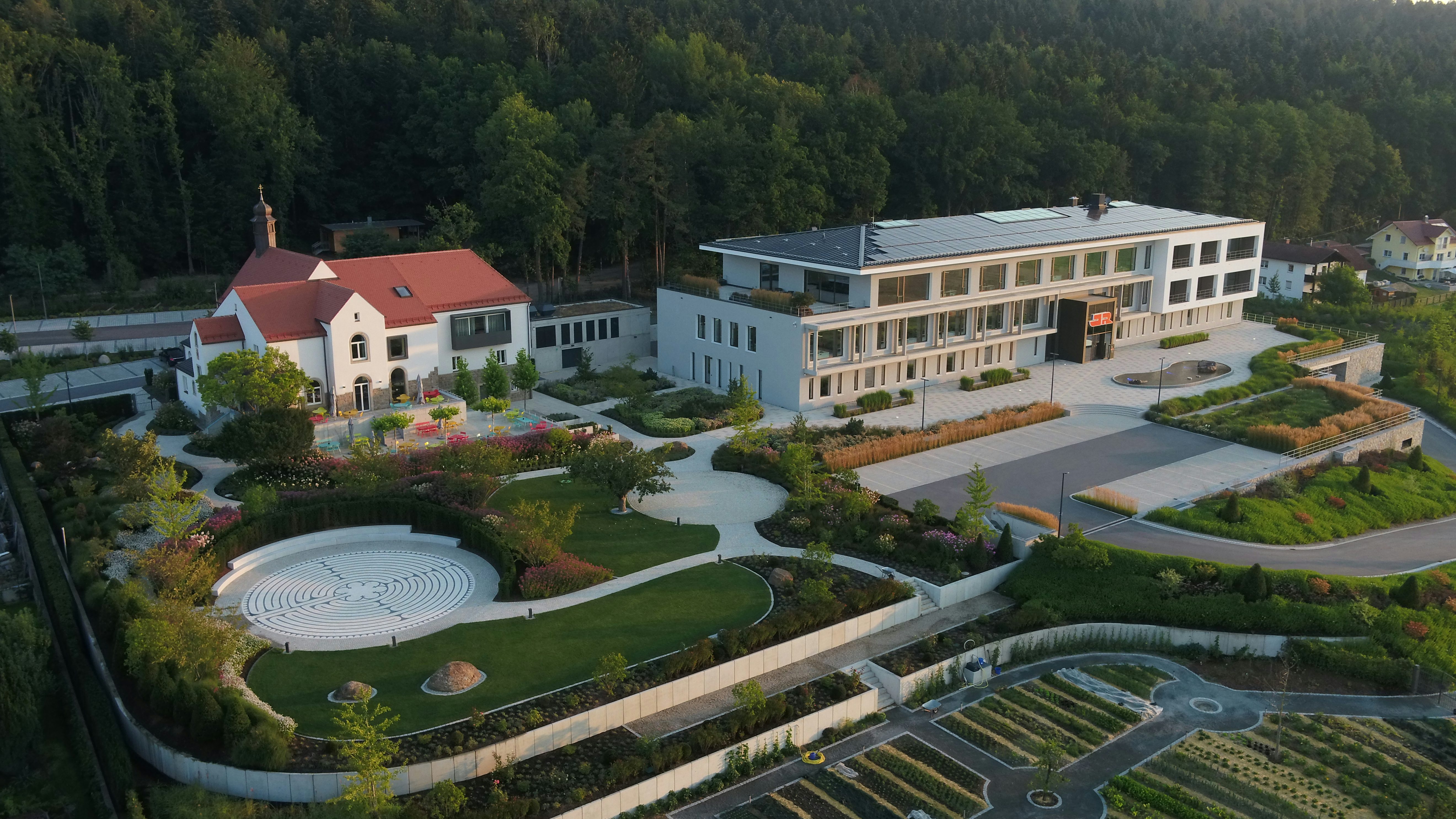 Luftaufnahme des Standort in Cham mit Bürogebäude, Garten und dem Mitarbeitendenrestaurant 's Kloster