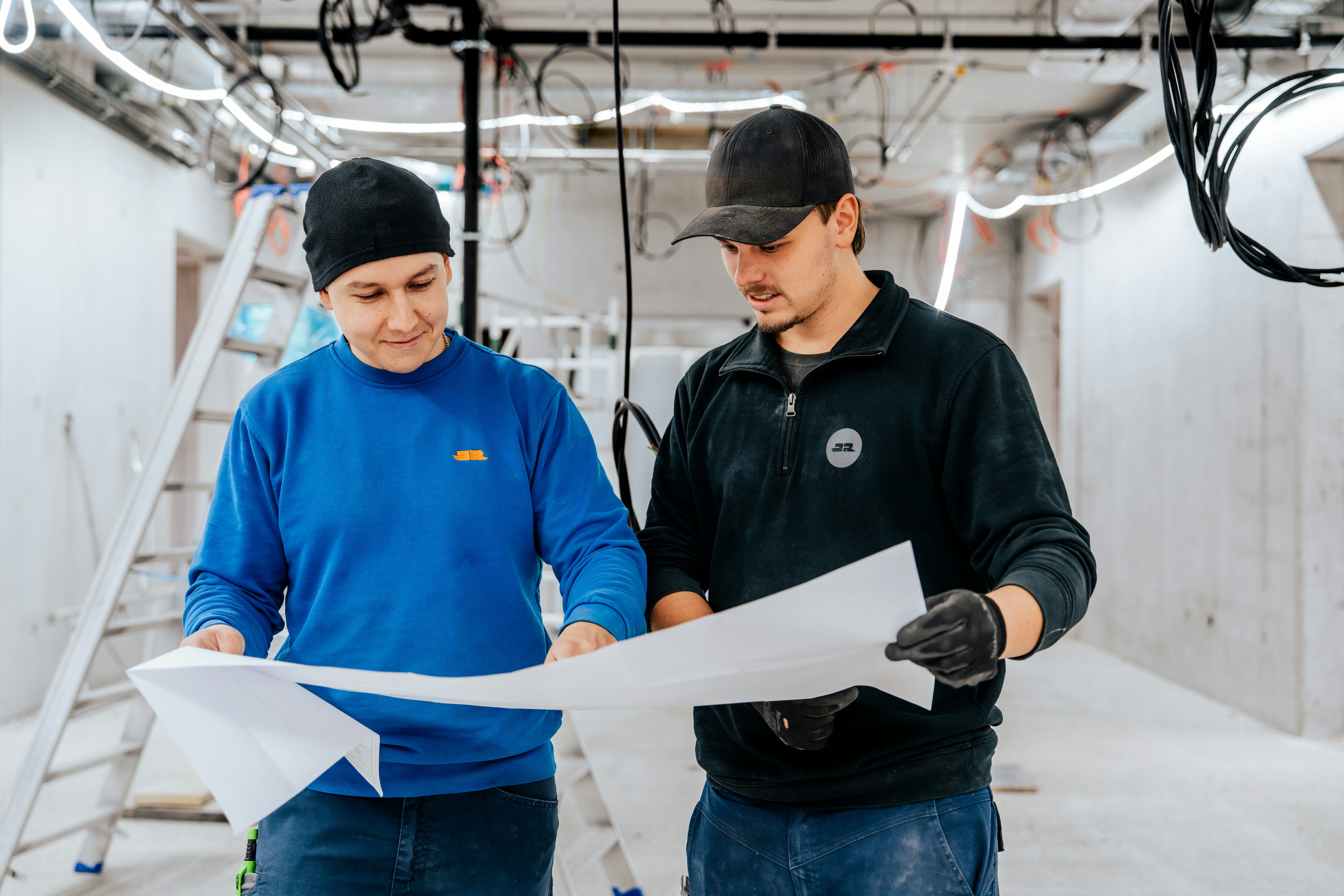 Zwei JR Mitarbeiter besprechen die Pläne für die Elektroinstallationen im Gebäude