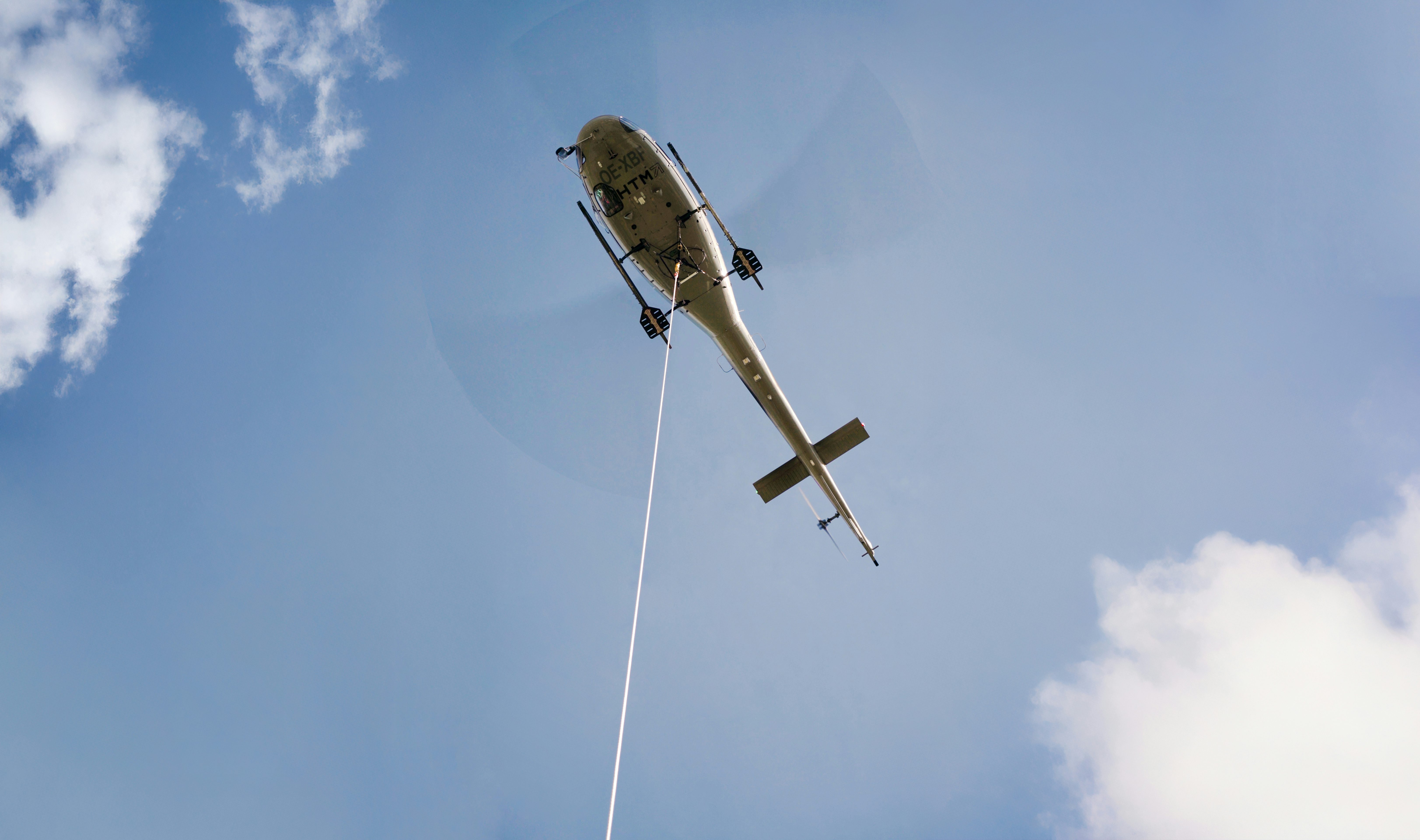 Der Helikopter fliegt über das Fußballfeld und transportiert dabei die Masten