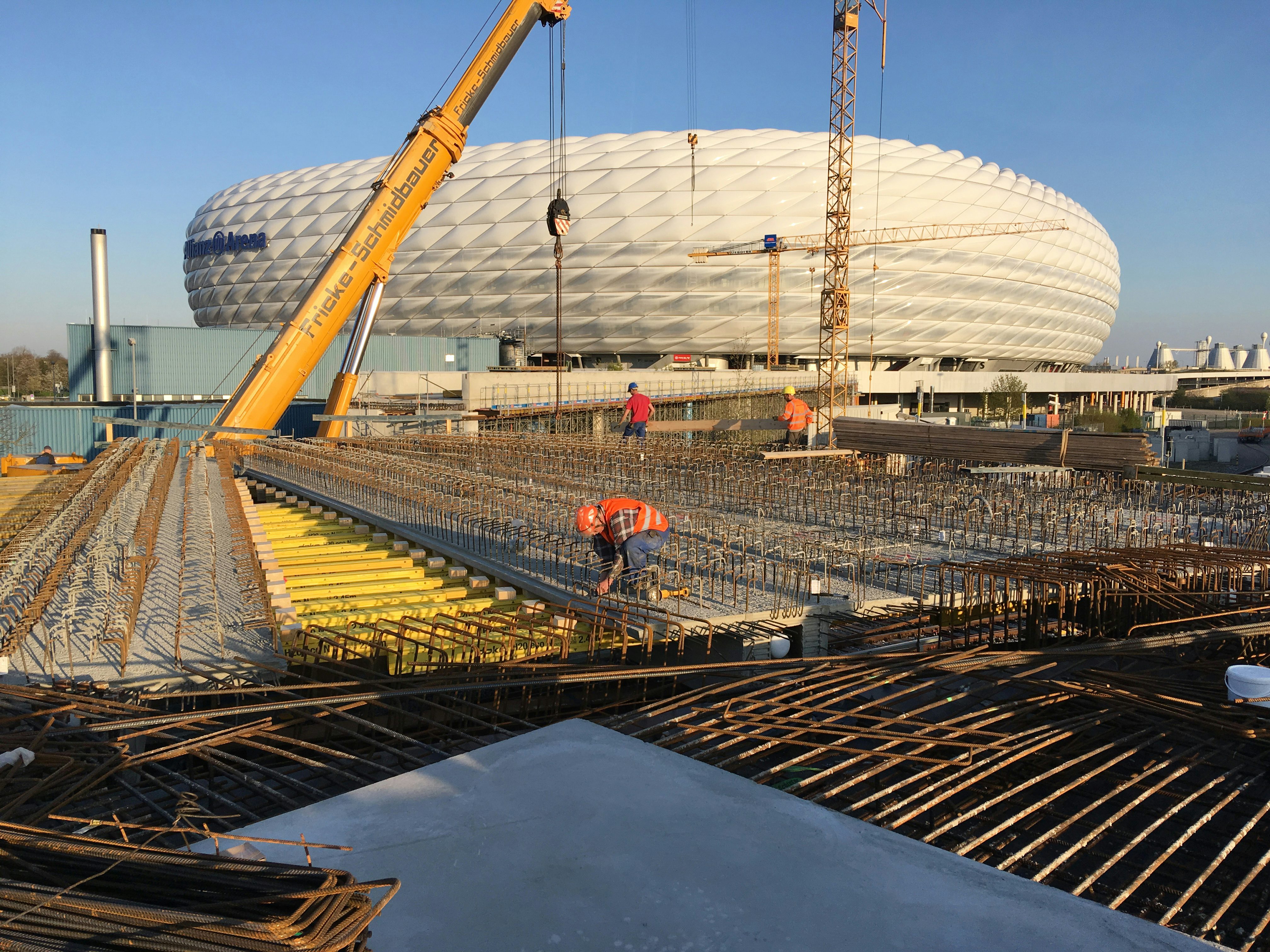 JR Arbeiter arbeiten bei Tag vor Allianz Arena, im Hintergrund sind Krane