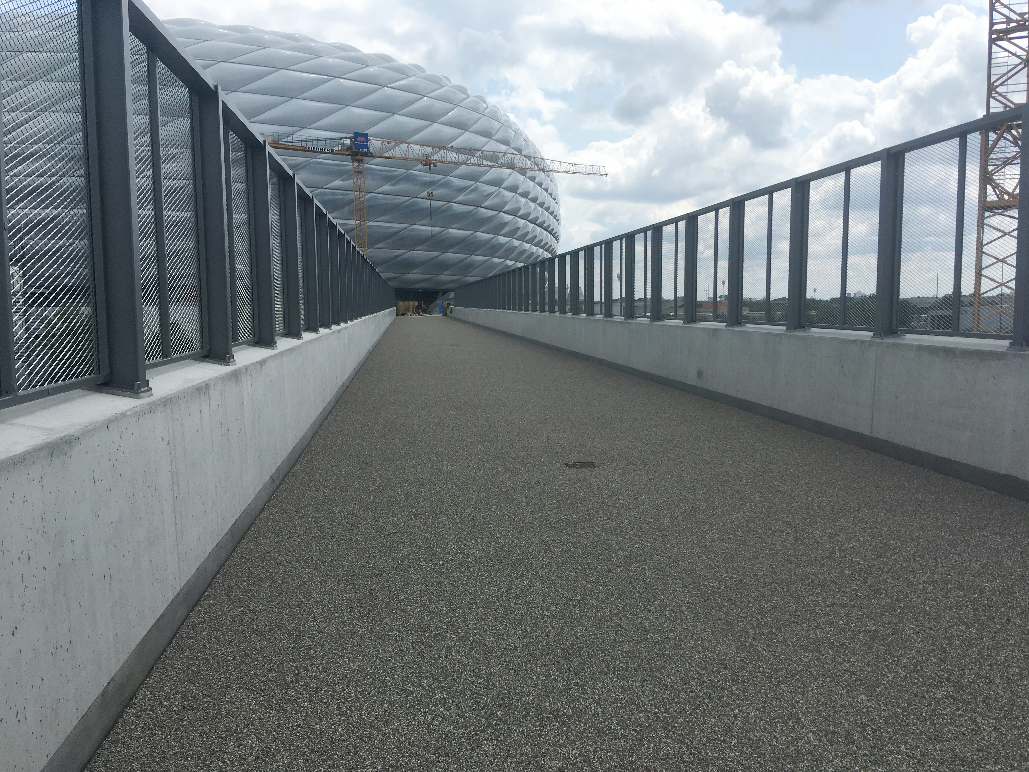 Die fertige Fußgängerüberführung mit Allianz Arena und Kran im Hintergrund