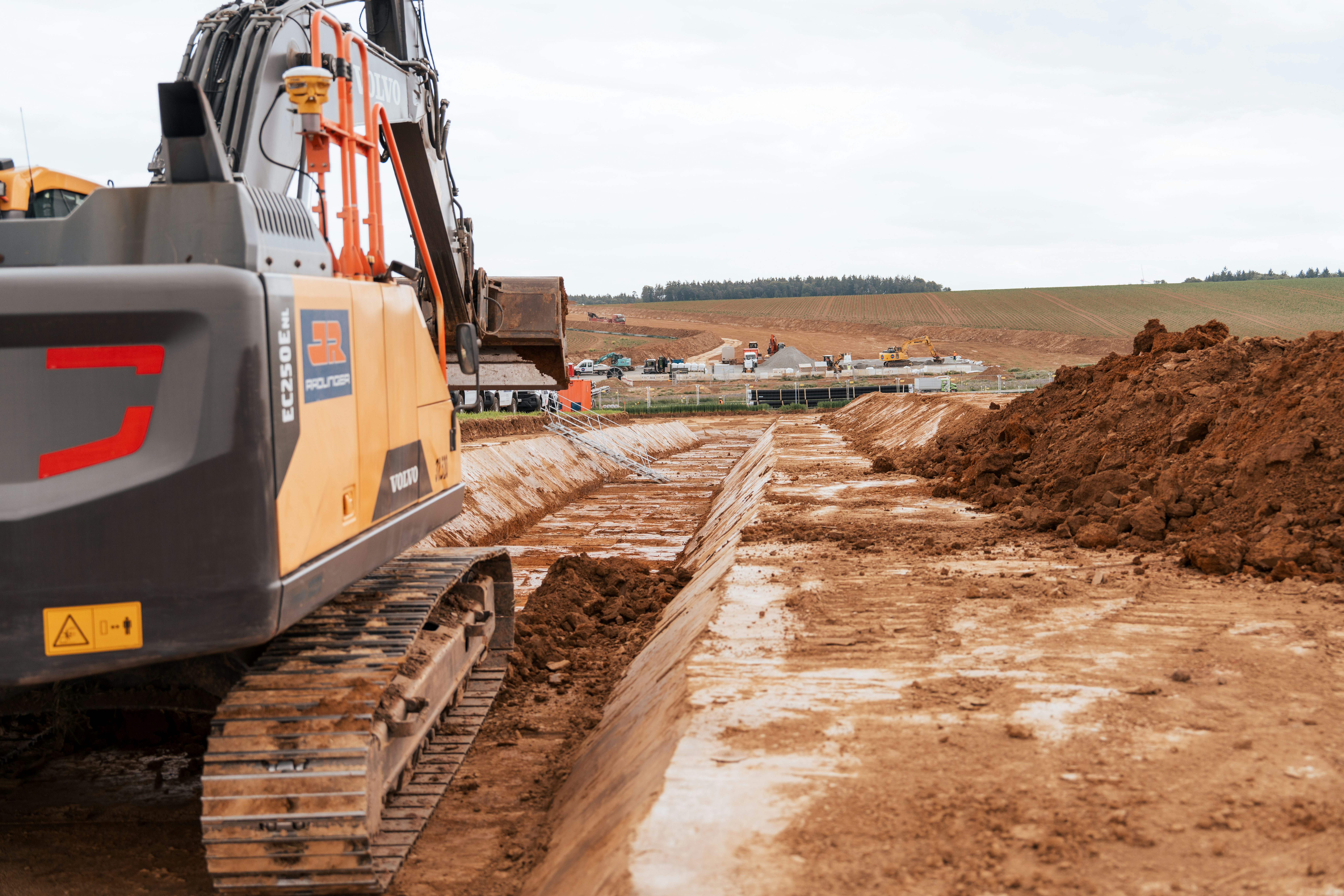 Aufnahme eines Baggers von der Seite hinten auf der Baustelle des SuedOstLink