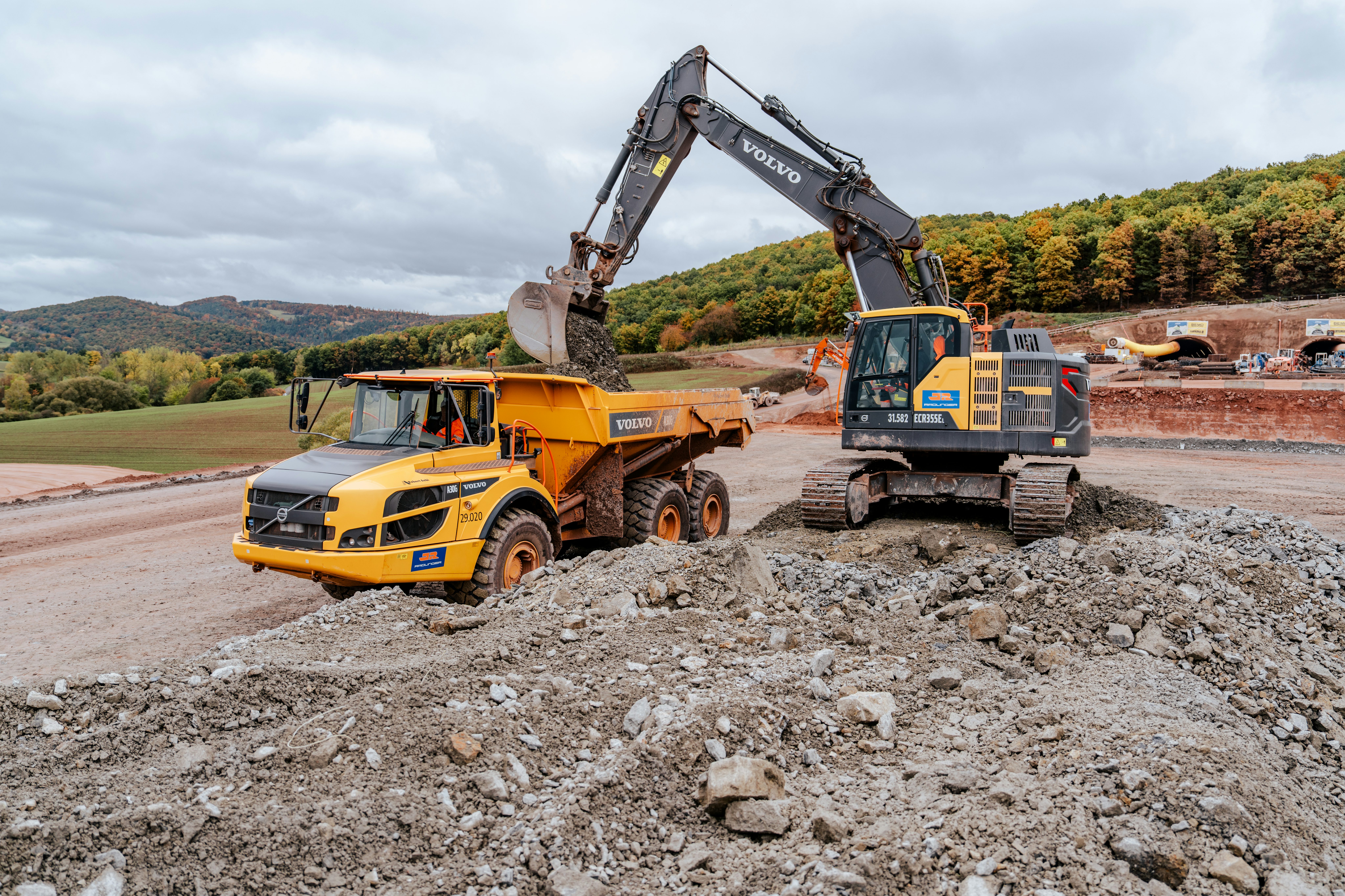 Bagger verlädt Schüttgut im Herbst vom Neubau des Tunnel Holstein der A 44