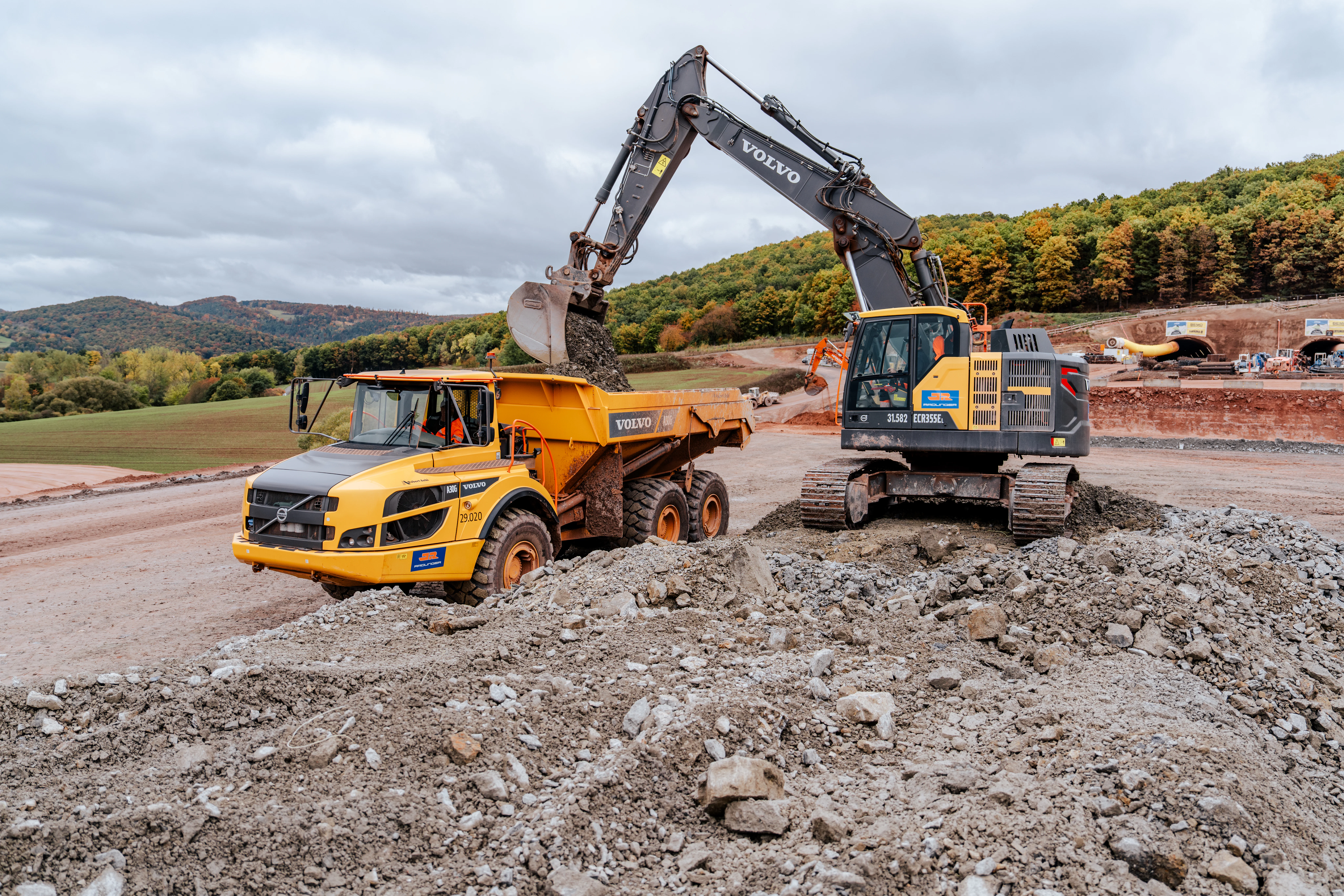 Bagger verlädt Schüttgut im Herbst vom Neubau des Tunnel Holstein der A 44