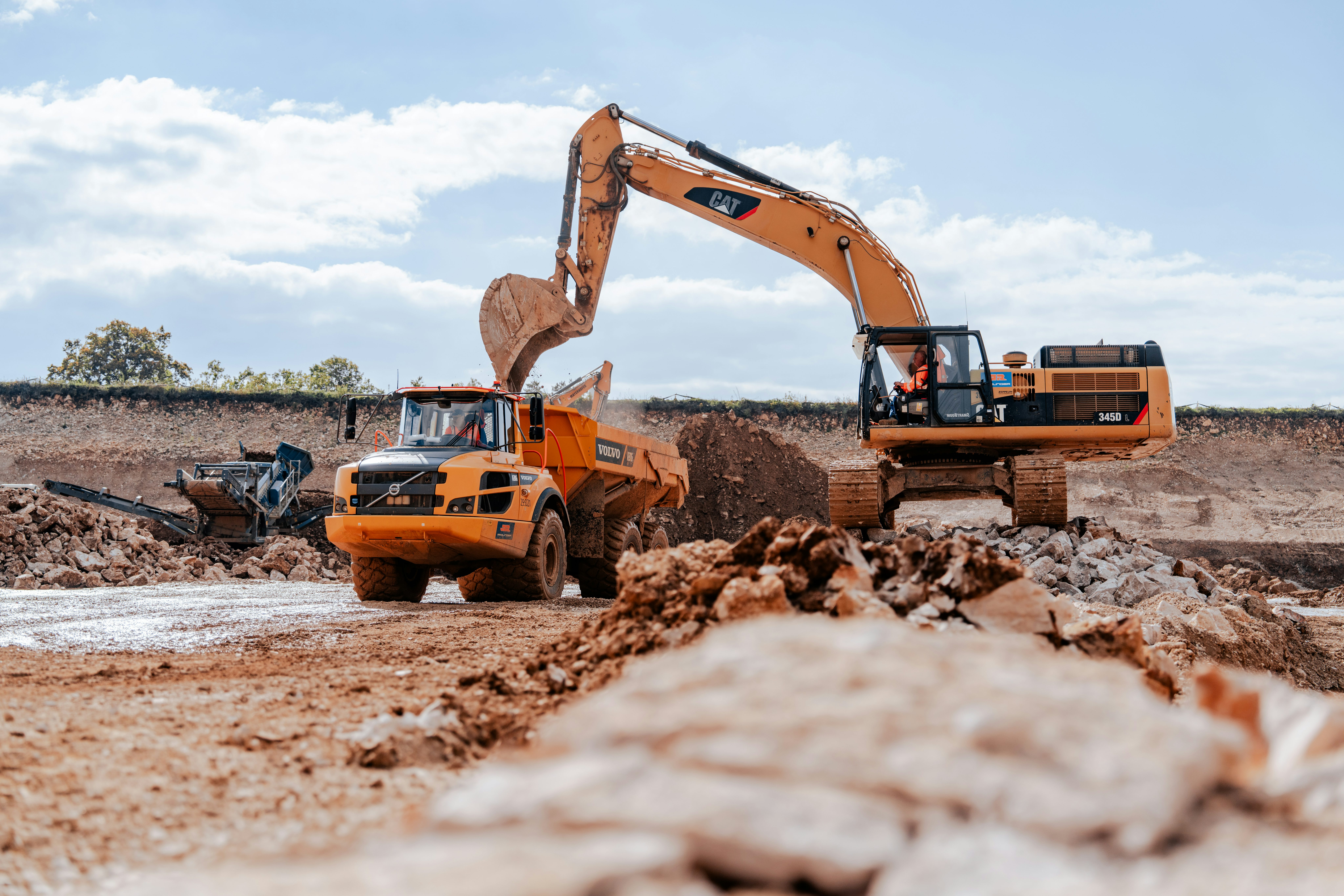 Pumpspeicherkraftwerk Happurg, Sanierung Oberbecken: Bagger belädt Dumper mit abgebautem Gestein, im Hintergrund Recycling-Anlage