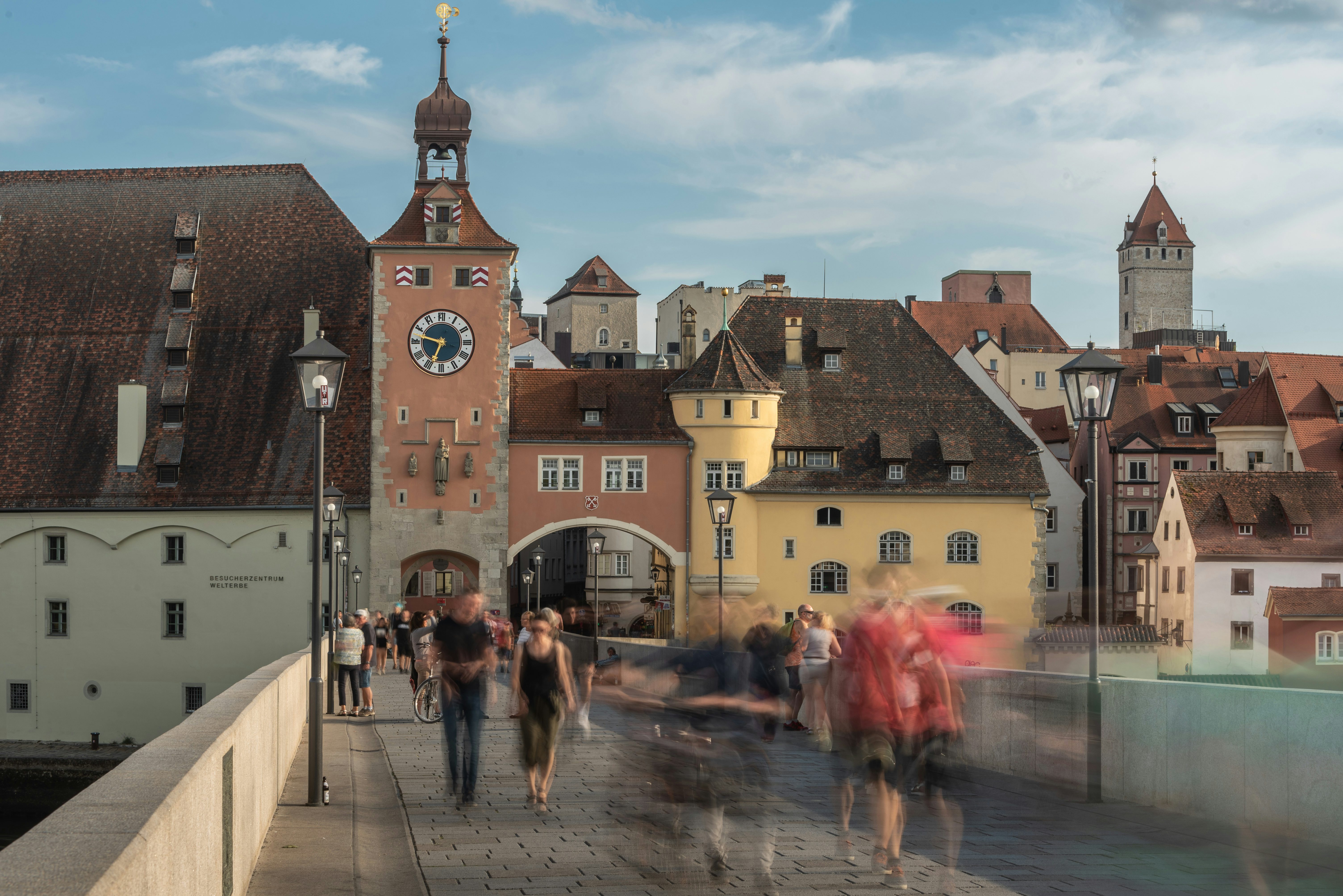 Personen gehen über die Steinerne Brücke in Regensburg