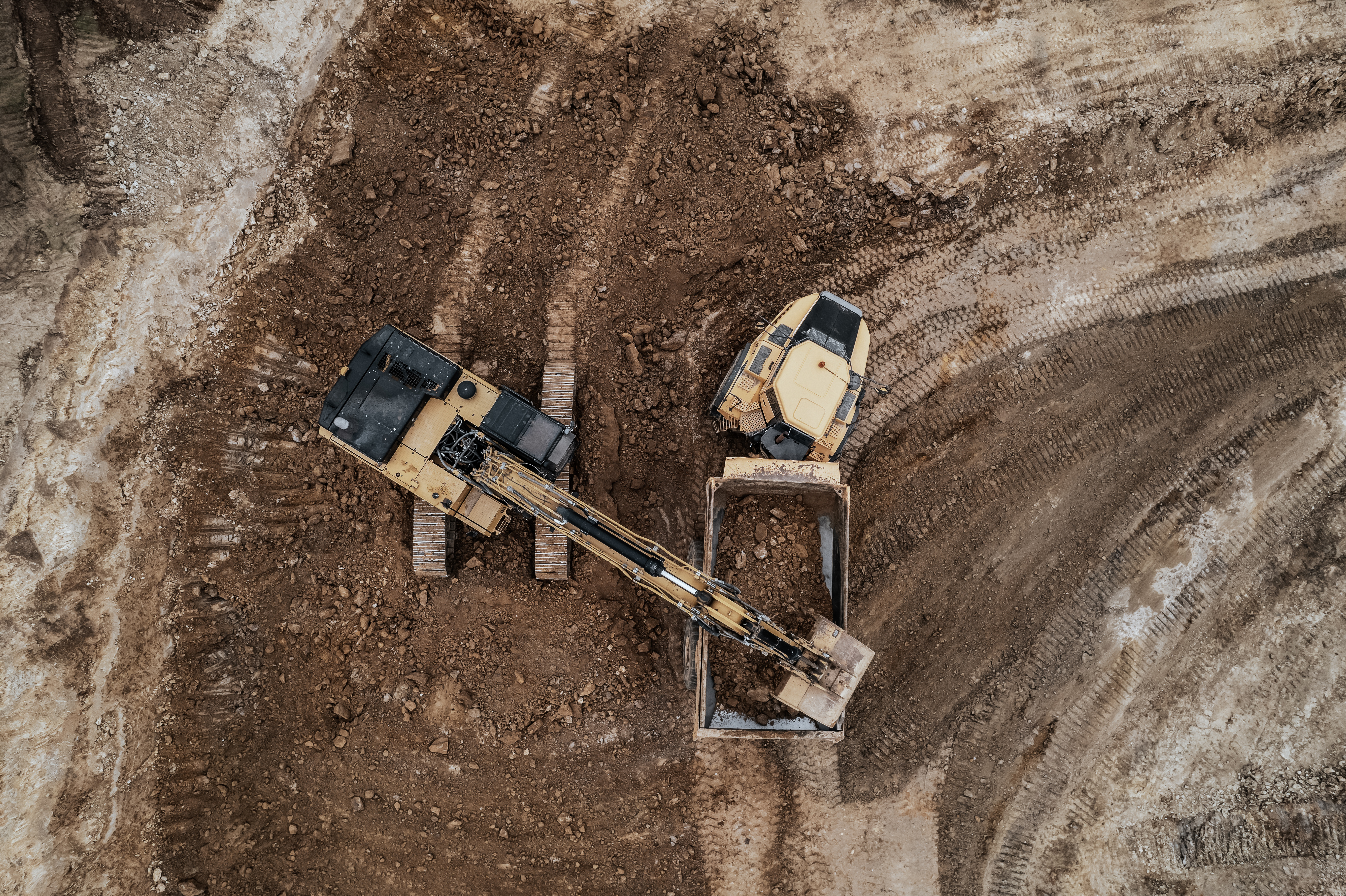 Rädlinger Erdbau: Bagger lädt Erde auf Dumper, Drohnenaufnahme