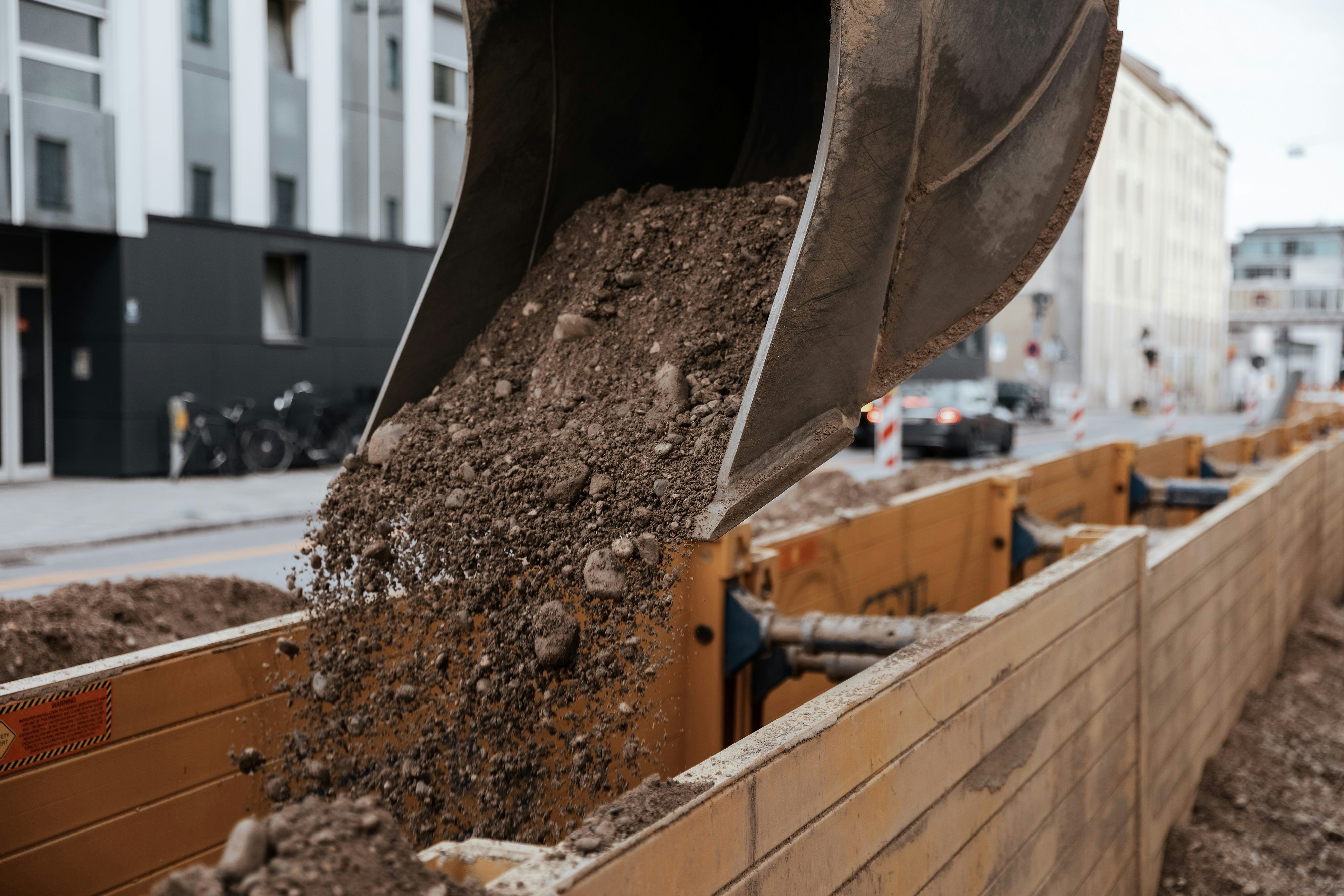 Baggerschaufel beim Auffüllen eines eingeschalten Rohrgrabens