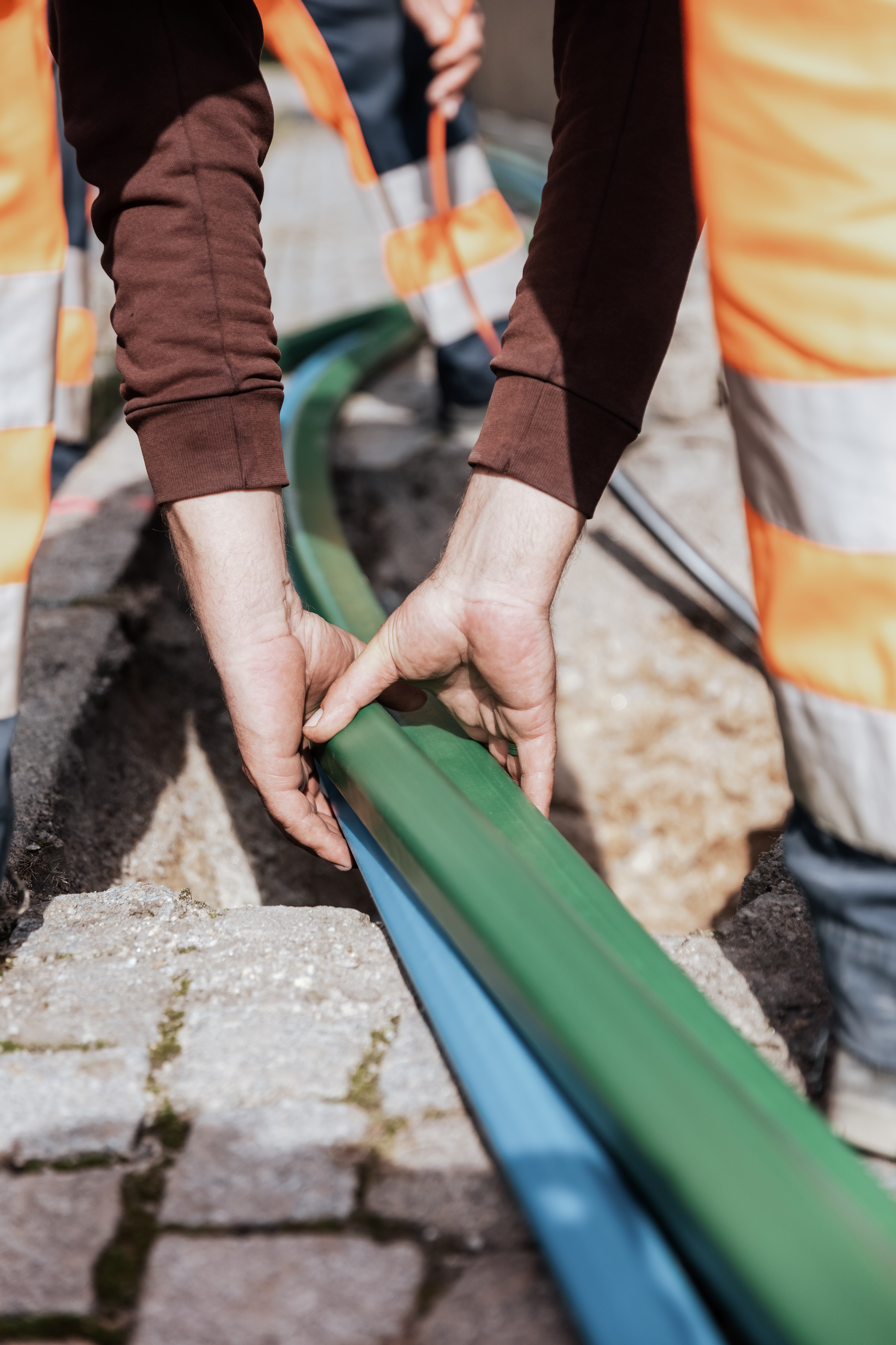 Rädlinger Netzbau: Mitarbeiter beim Einzug von Leerrohren in einen Leitungsgraben