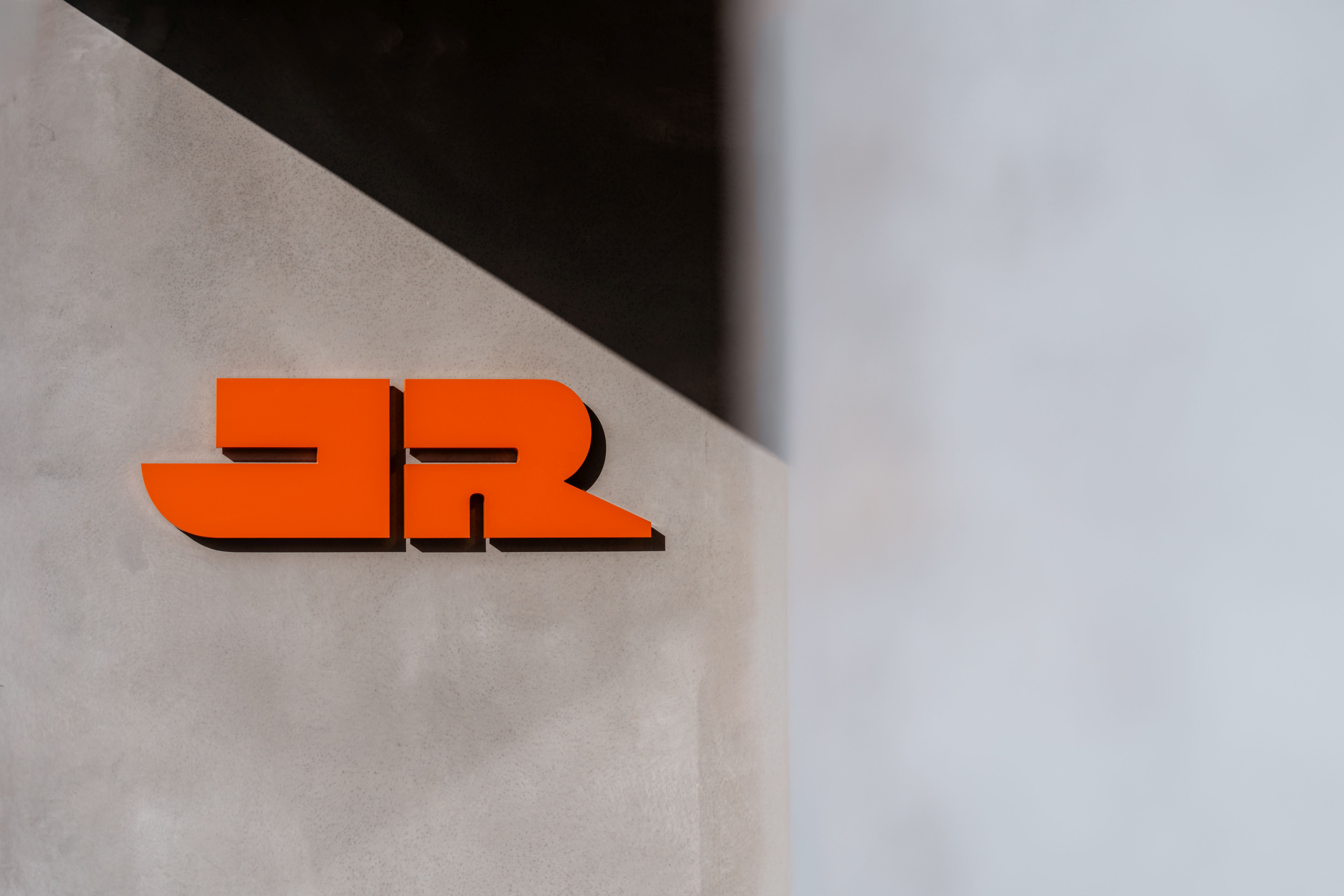 Das orange JR Logo auf einer grauen Betonwand