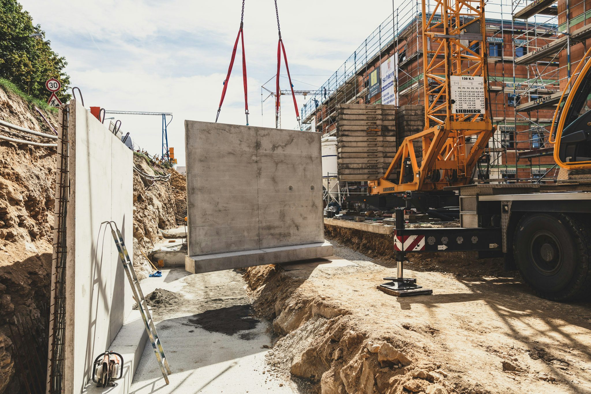 Auf einer Baustelle wird ein Beton-Fertigteil mit Hilfe eines Krans eingehoben