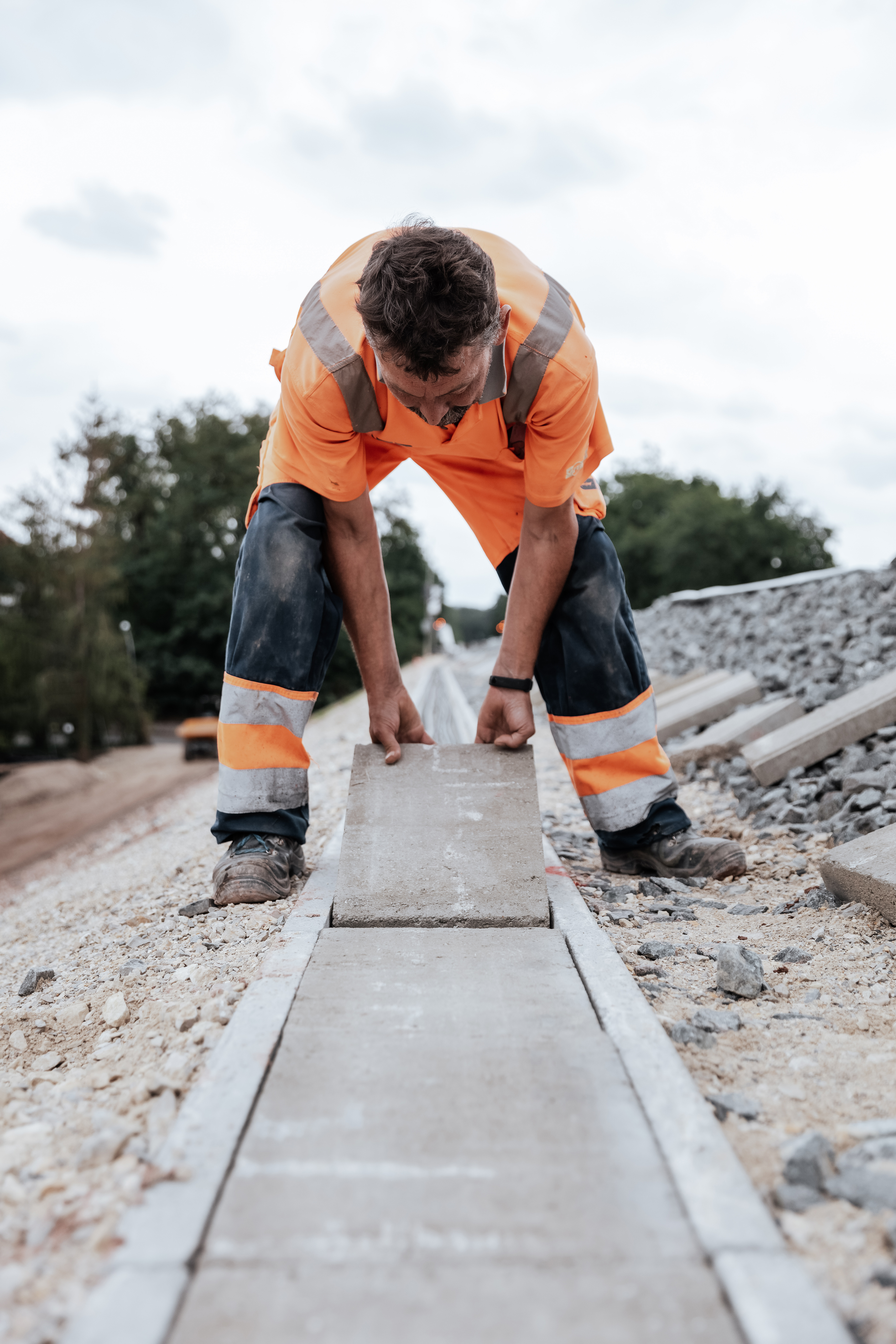 Rädlinger Mitarbeiter verschließt Kabelkanal entlang einer Bahnstrecke mit Pflasterplatten