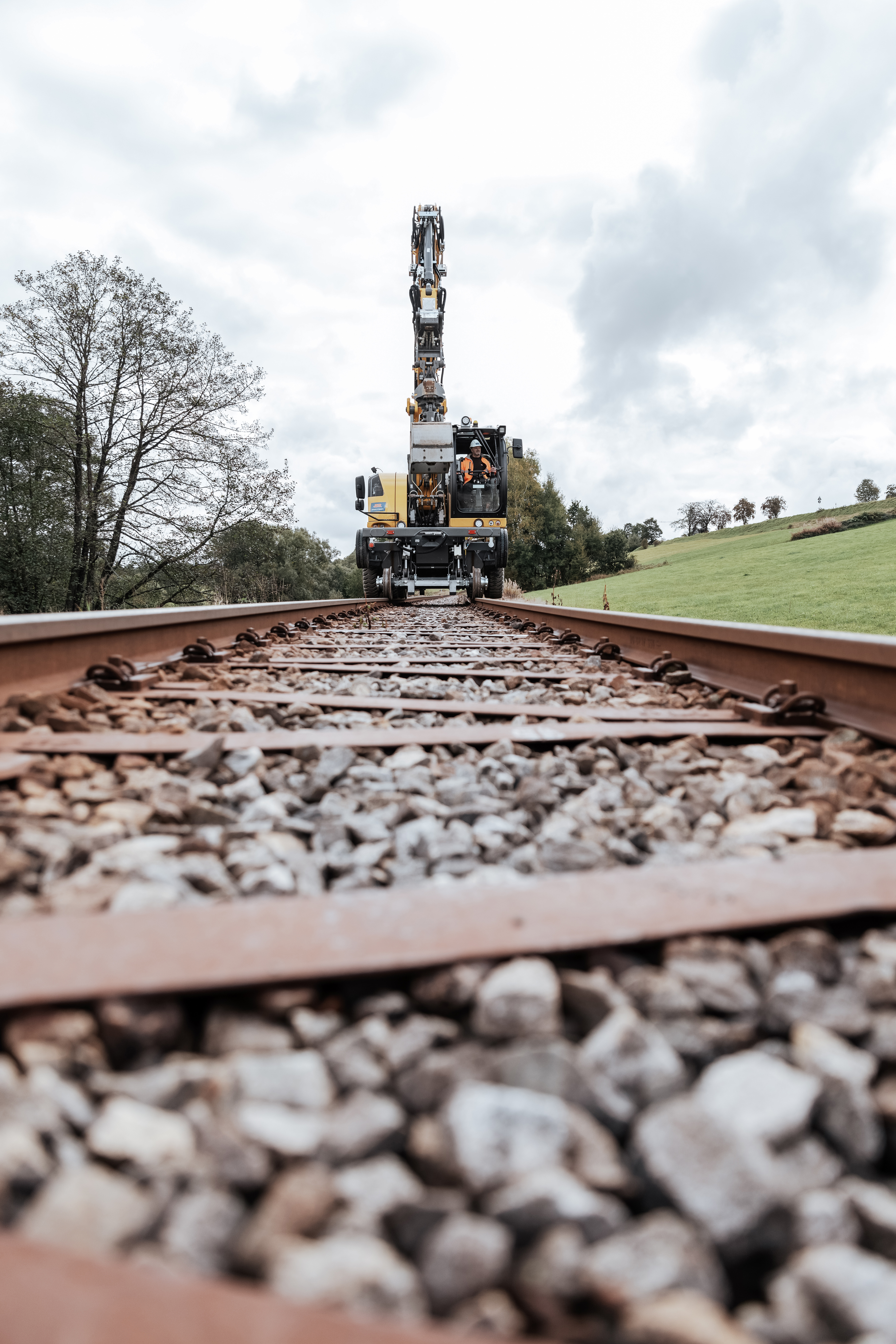 Zweiwegebagger fährt auf Bahngleis